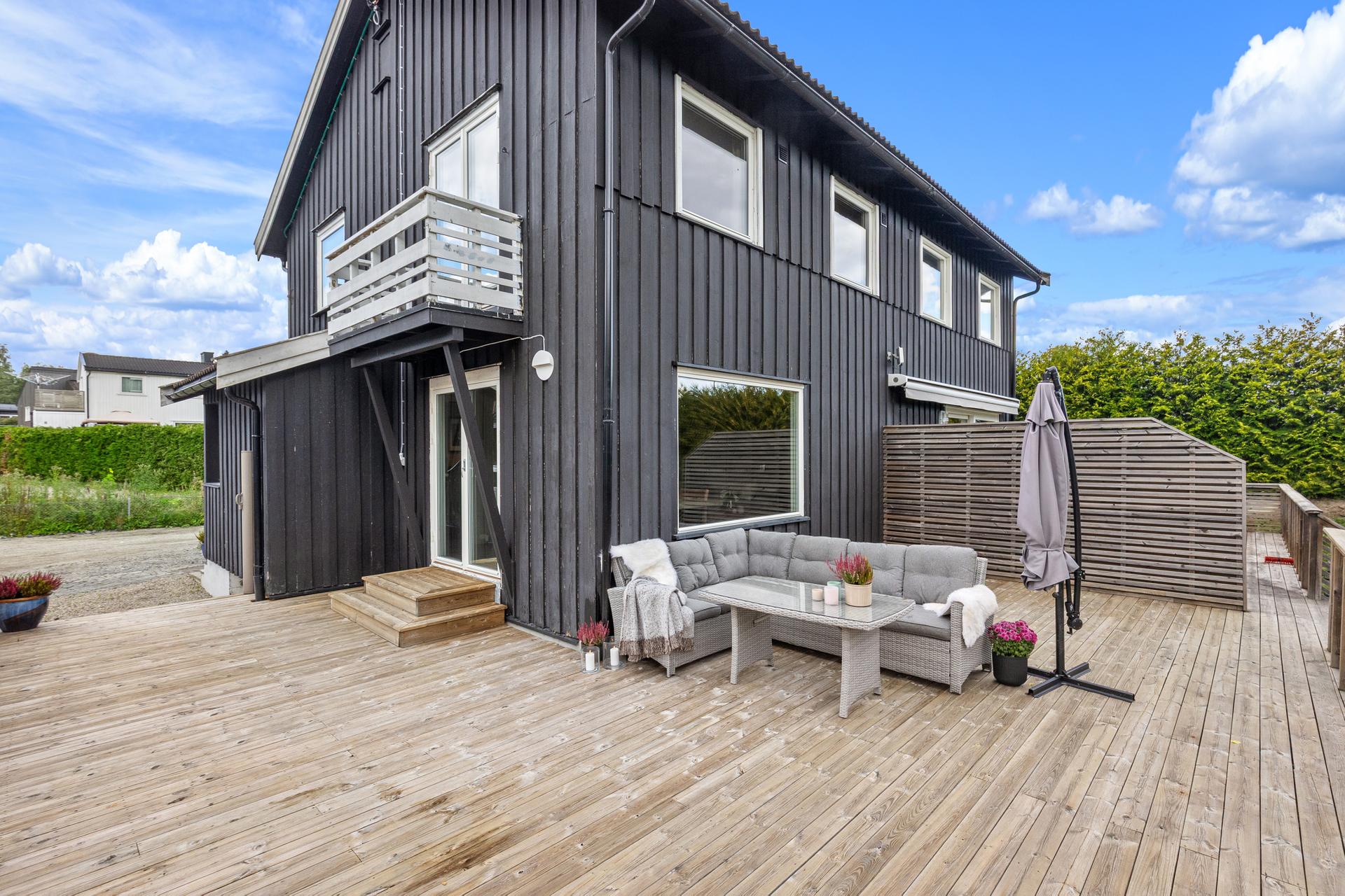 Stor terrasse på bakkeplan med direkte utgang fra stuen og god plass til sittegruppe.. Bilde nummer 3 av 3