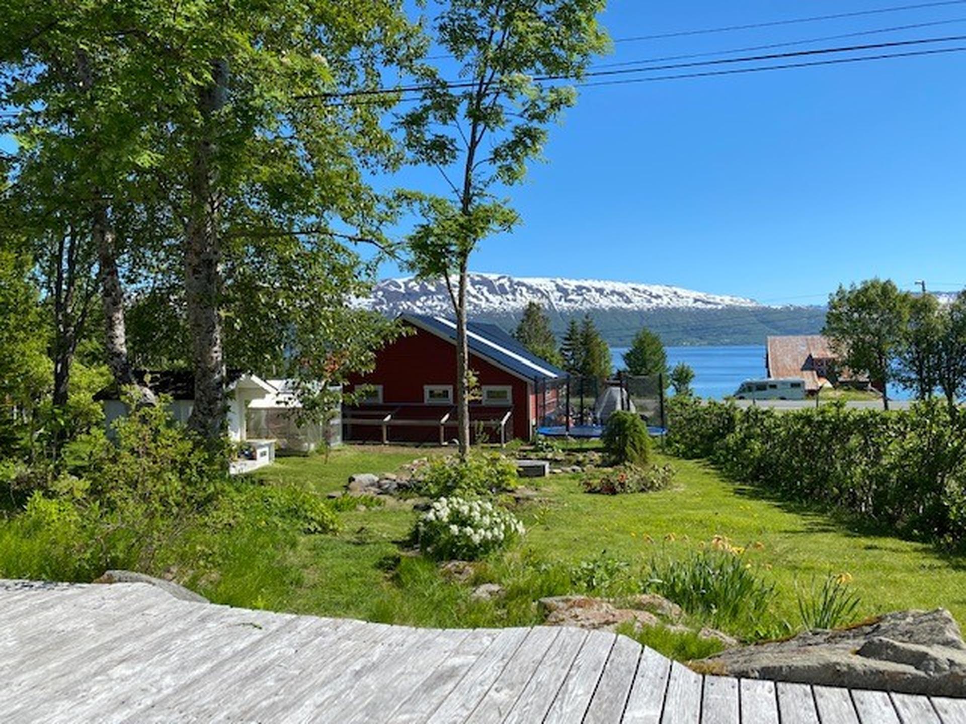 Terrasse i tre med utsyn over hagen, garasjen og fjorden.. Bilde nummer 2 av 3