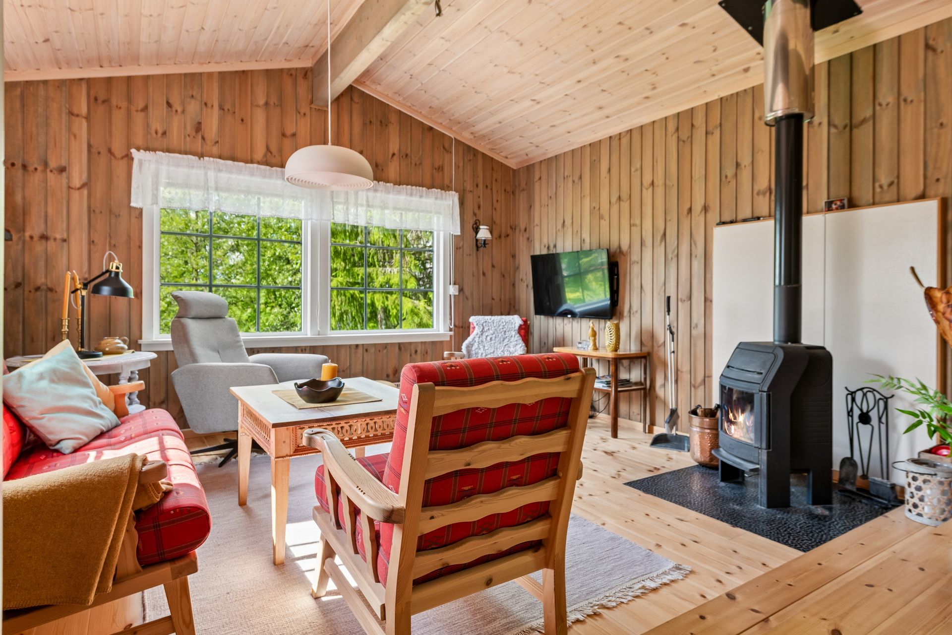 Hytta har gjennomgående heltre gulv og trepanel, og en peisovn i stuen for varme og hygge.. Bilde nummer 2 av 3