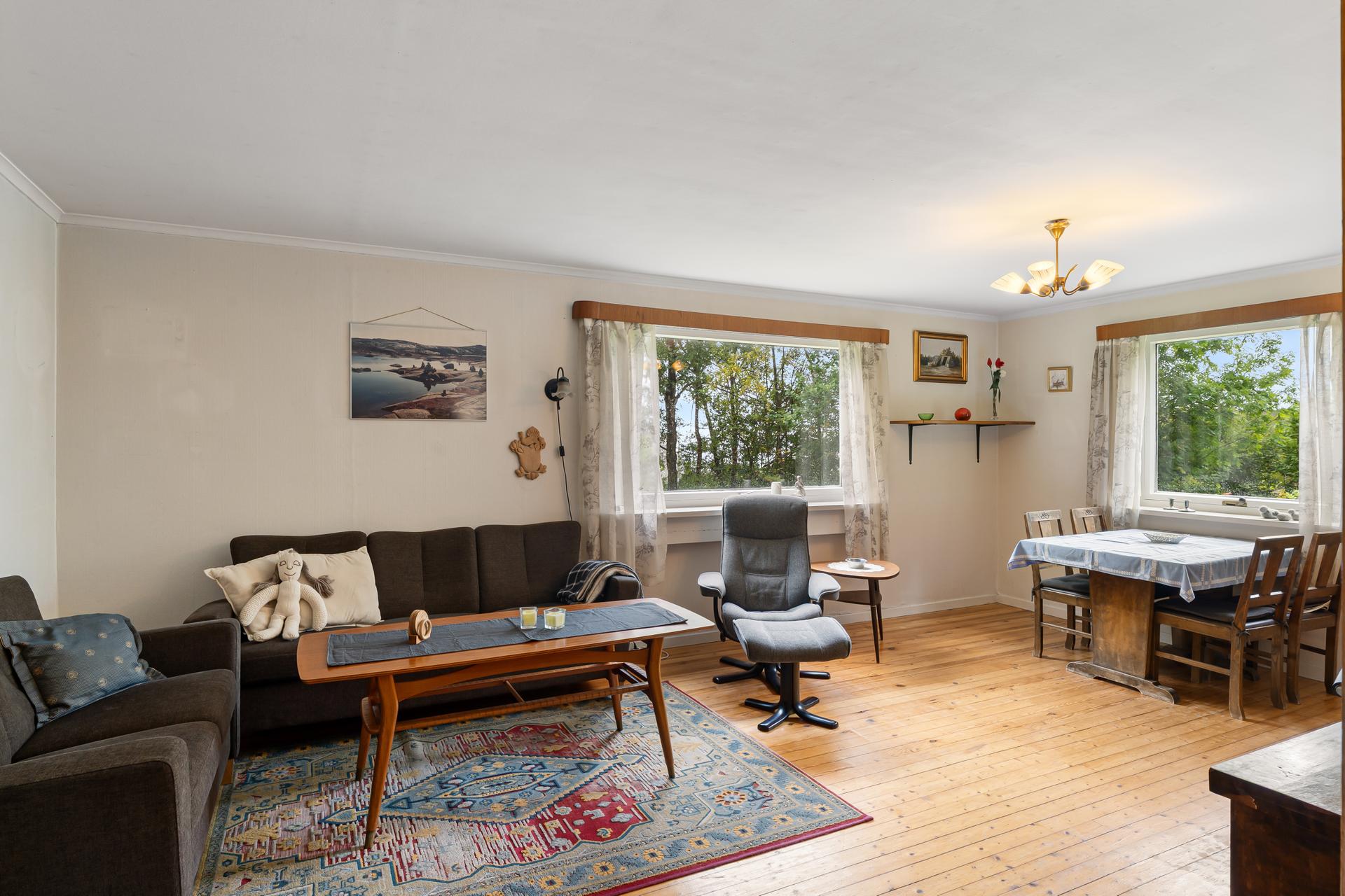 Stuen har tregulv i furu og god plass til både sofagruppe og spisebord.. Bilde nummer 3 av 3