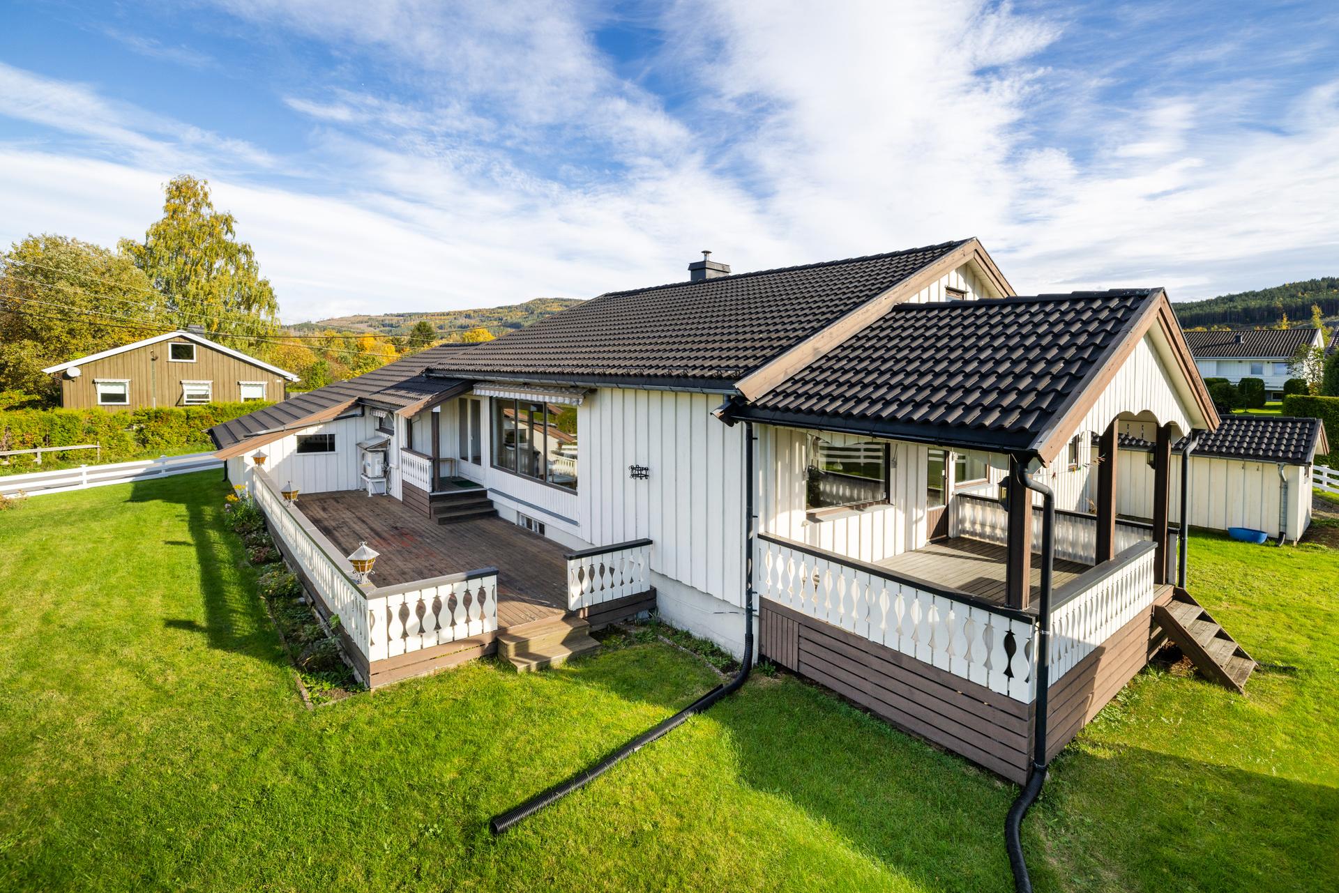 Frittstående enebolig oppført over ett plan med kjeller, terrasse og takoverbygget veranda.. Bilde nummer 2 av 3