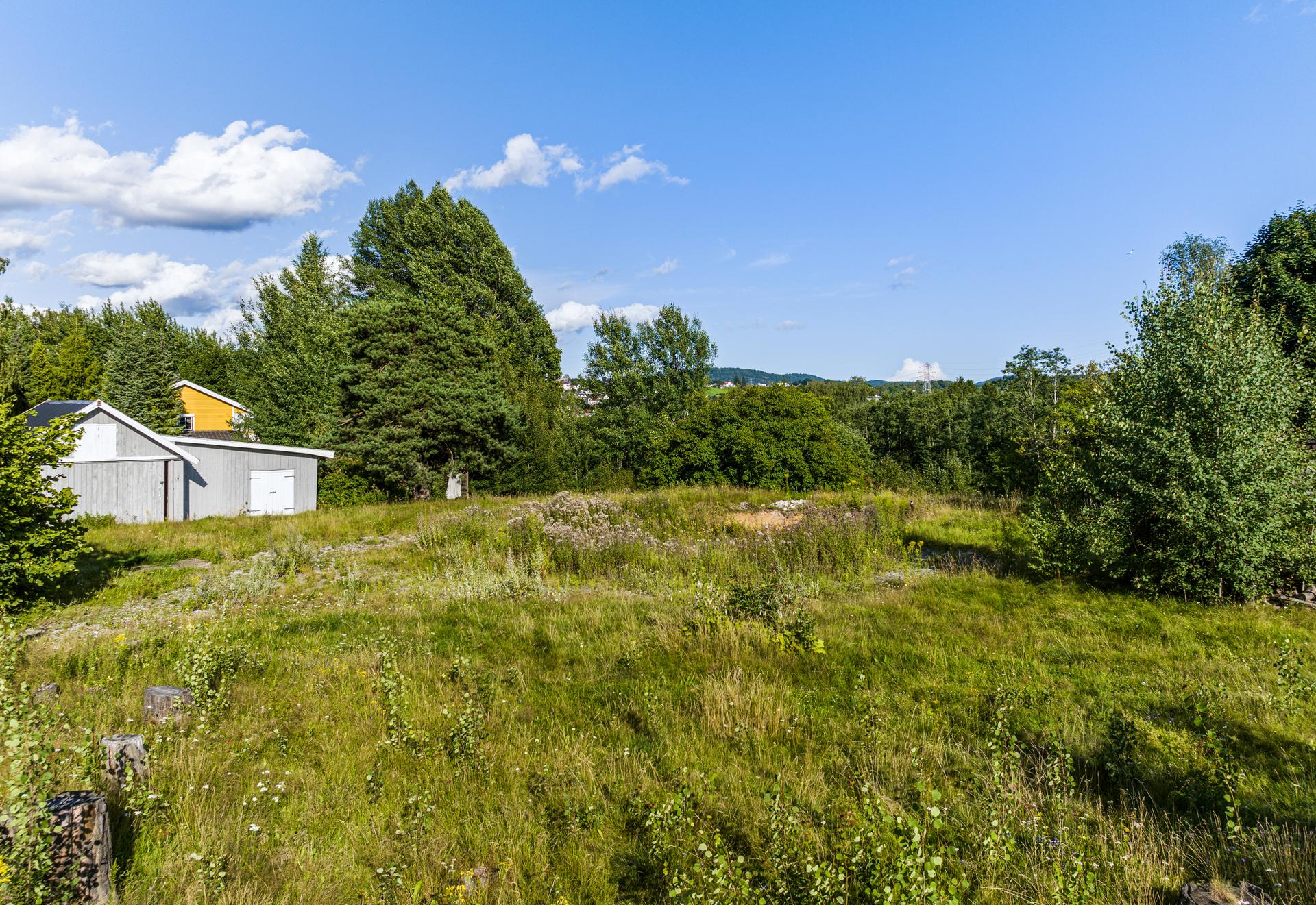 Eiendommen består hovedsakelig av naturtomt med trær og busker. Det er gruset innkjørsel til eiendommen fra Granegården.. Bilde nummer 3 av 3