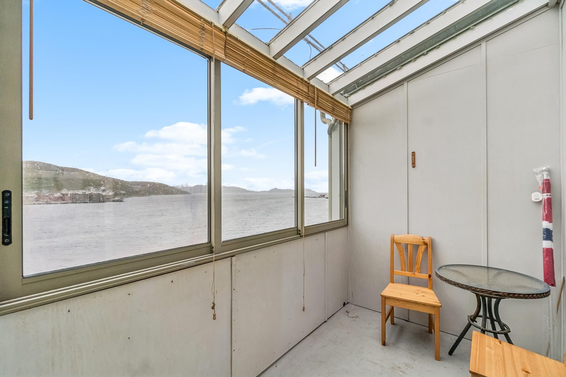 Innglasset balkong med utsikt over fjorden og plass til sittegruppe.. Bilde nummer 2 av 3