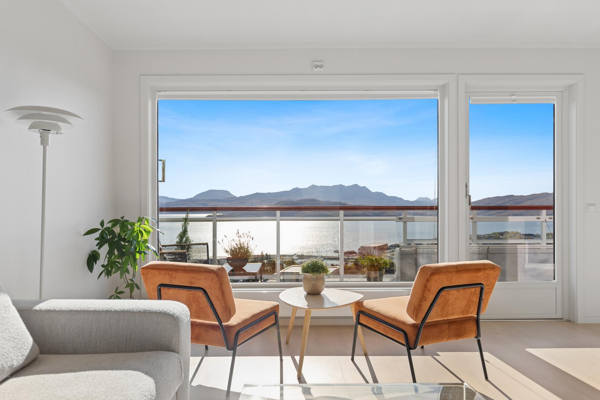 Store vindusflater i stuen rammer inn utsikten mot fjorden og fjellene.. Bilde nummer 3 av 3