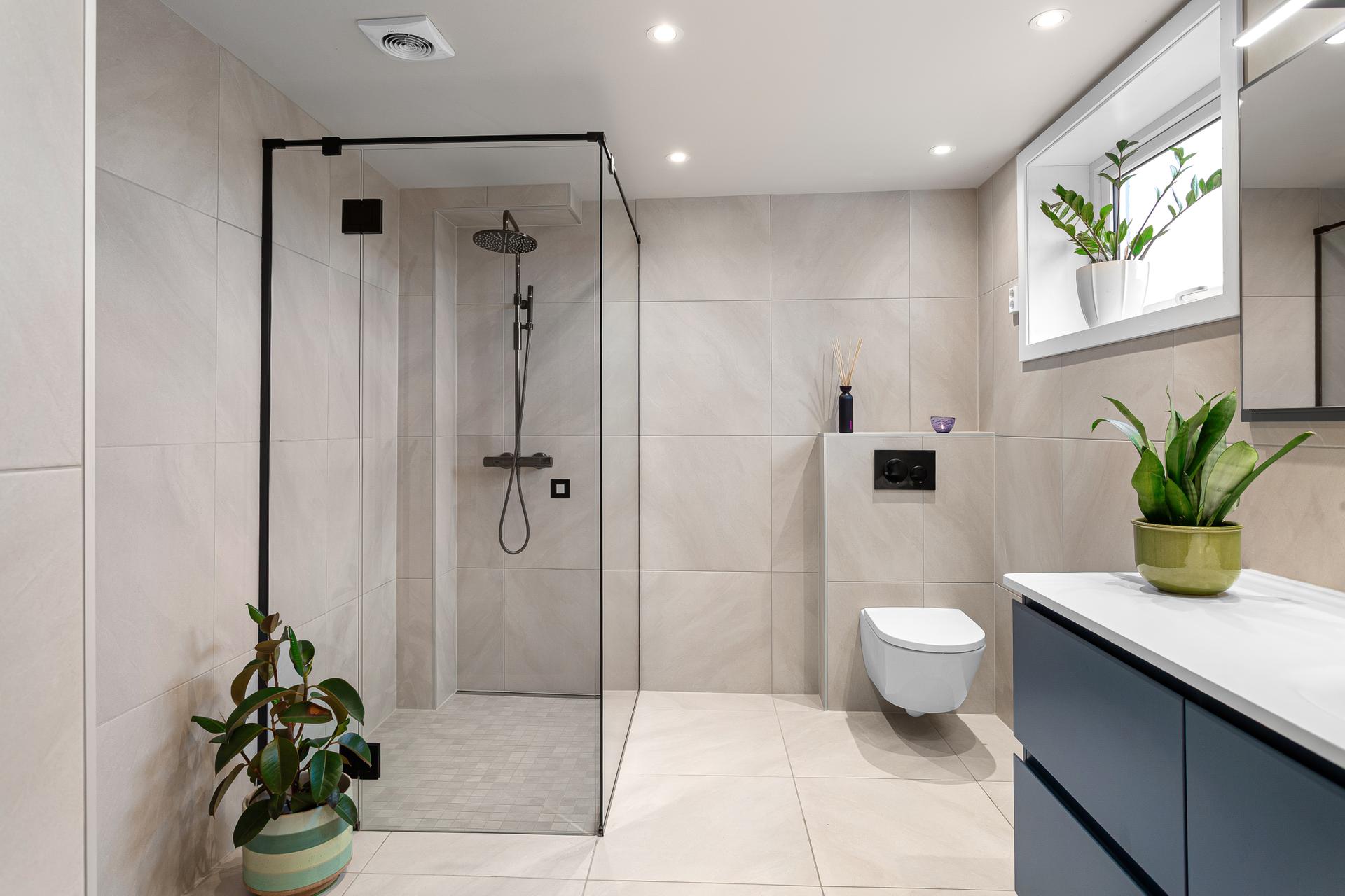 Badet i underetasjen er innredet med store fliser, dusjhjørne med regndusj og vegghengt toalett. Foto: Ole Thoresen. Bilde nummer 2 av 3