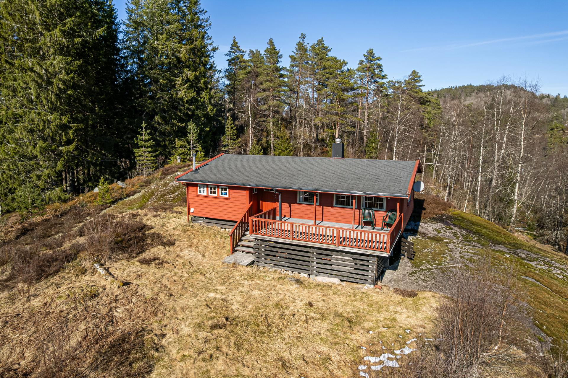 Fritidsbolig fra 1974, oppført med bindingsverkskonstruksjon på pilarer. Hytta har liggende bordkledning og tak tekket med pappshingel.. Bilde nummer 2 av 3