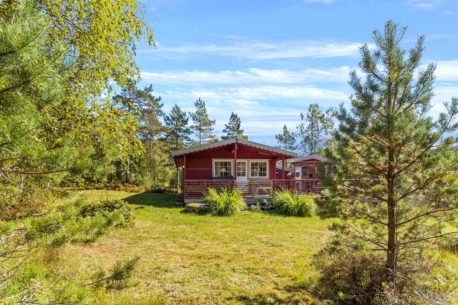 Fritidseiendommen ligger skjermet til i terrenget med en stor, sammenhengende terrasse og tilhørende utestue.. Bilde nummer 2 av 3