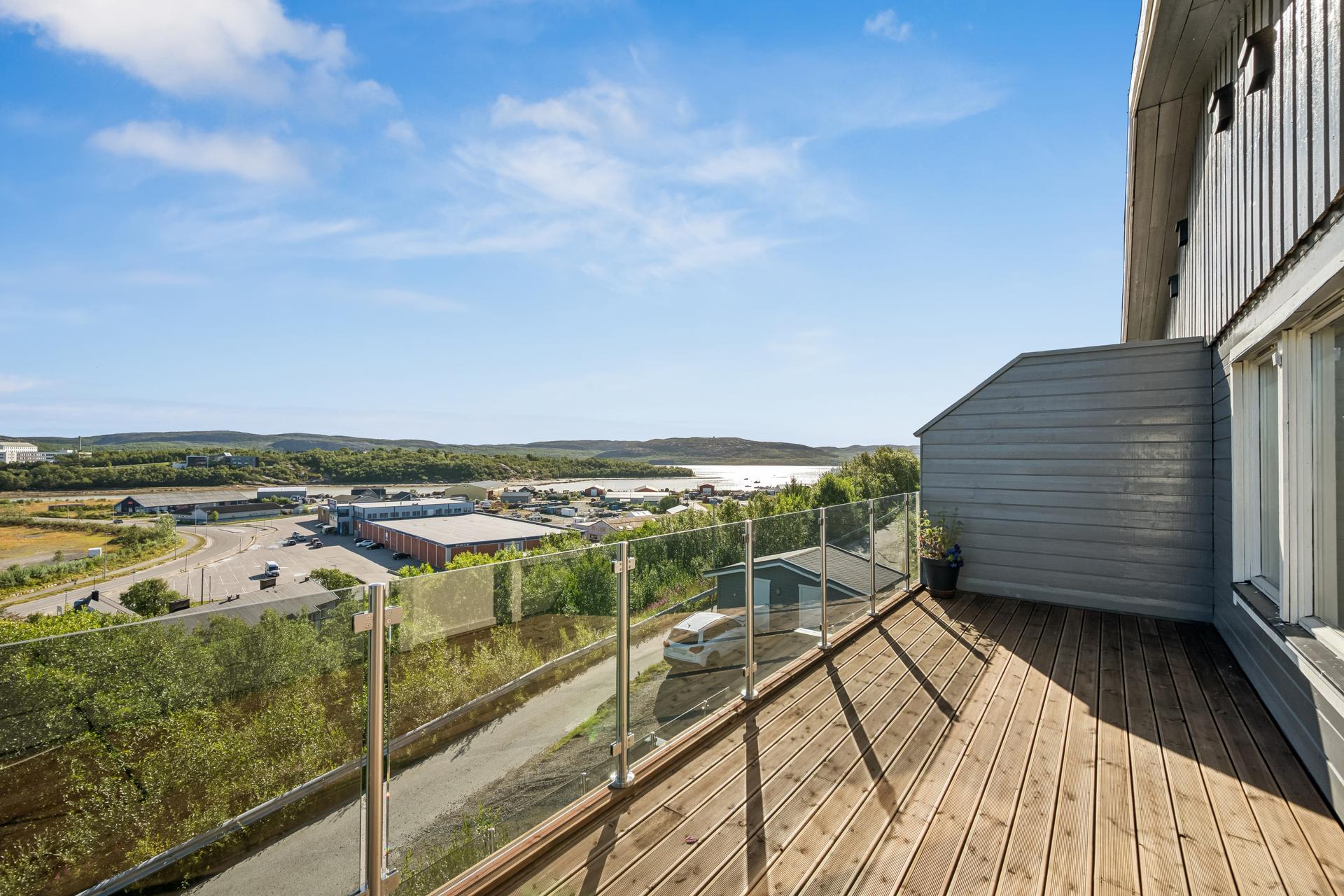Stor terrasse med glassrekkverk og vidstrakt utsikt mot fjorden og landskapet.. Bilde nummer 3 av 3