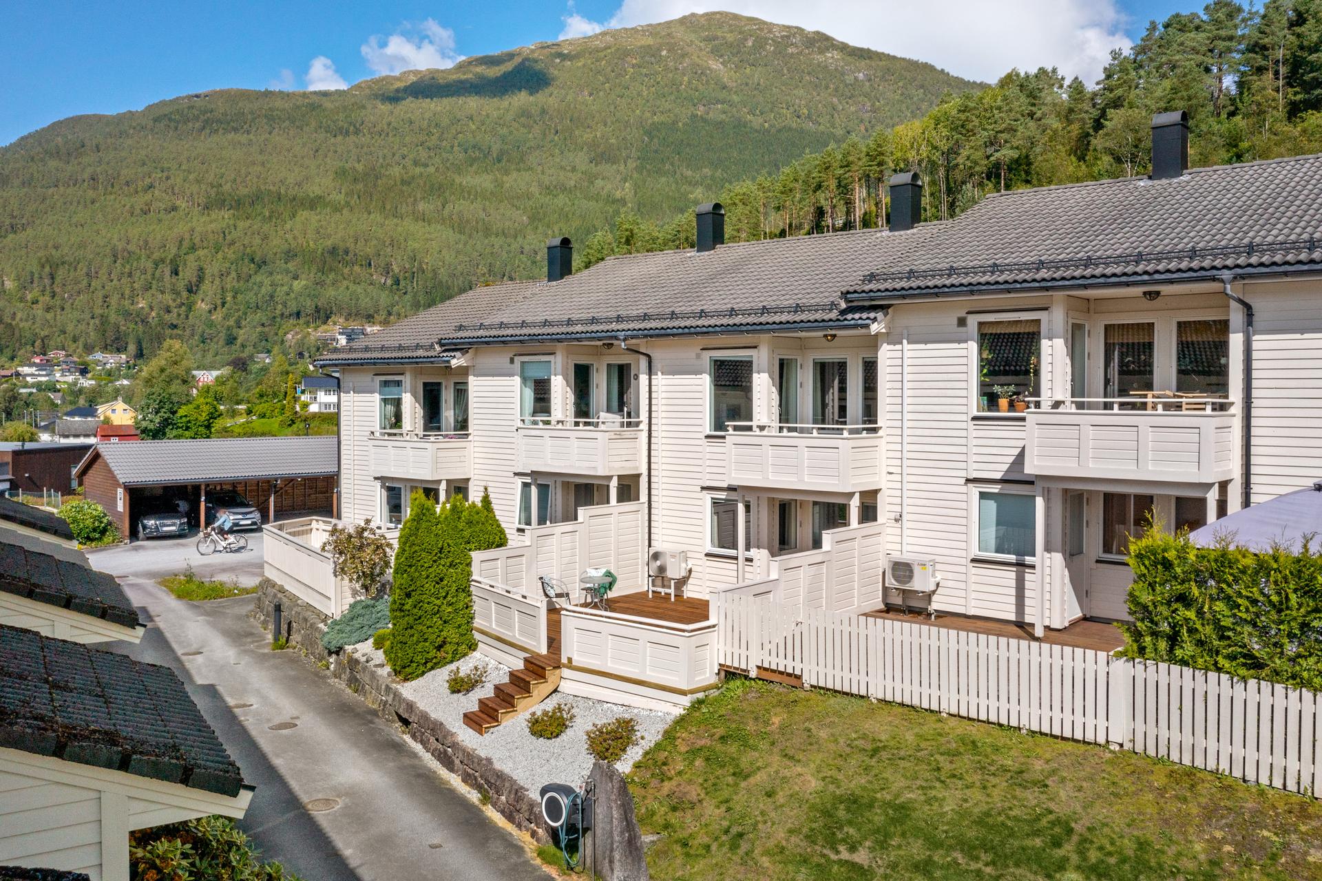 Rekkjehus over to plan med terrasse, to overbygde altanar og parkeringsplass i carportrekke.. Bilde nummer 2 av 3
