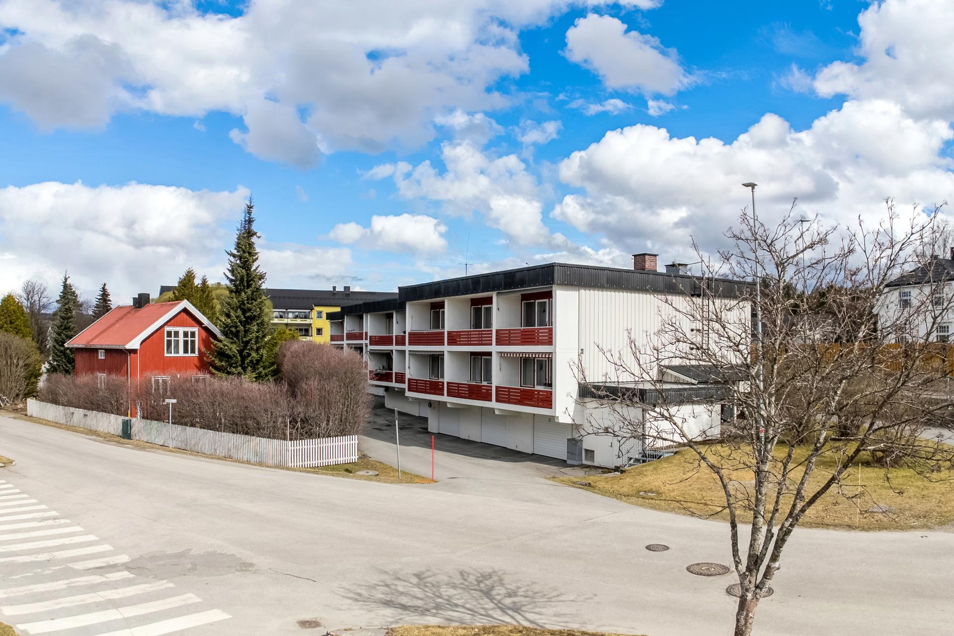 Fasade. Leiligheten ligger i høy 1. etasje på den vestre delen med garasjer i sokkeletasjen . Bilde nummer 3 av 3