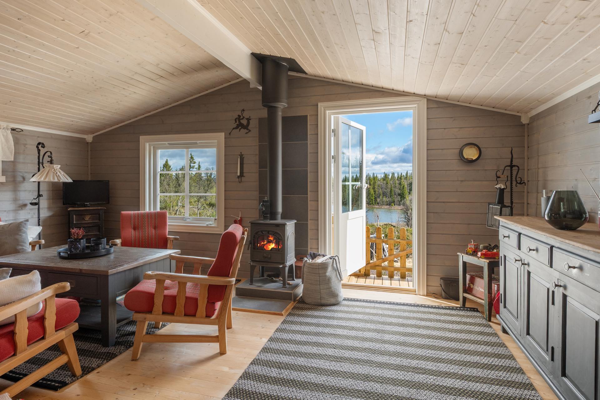 Stua har en sentralt plassert vedovn for varme og hygge, og utgang til den ene terrassen.. Bilde nummer 3 av 3