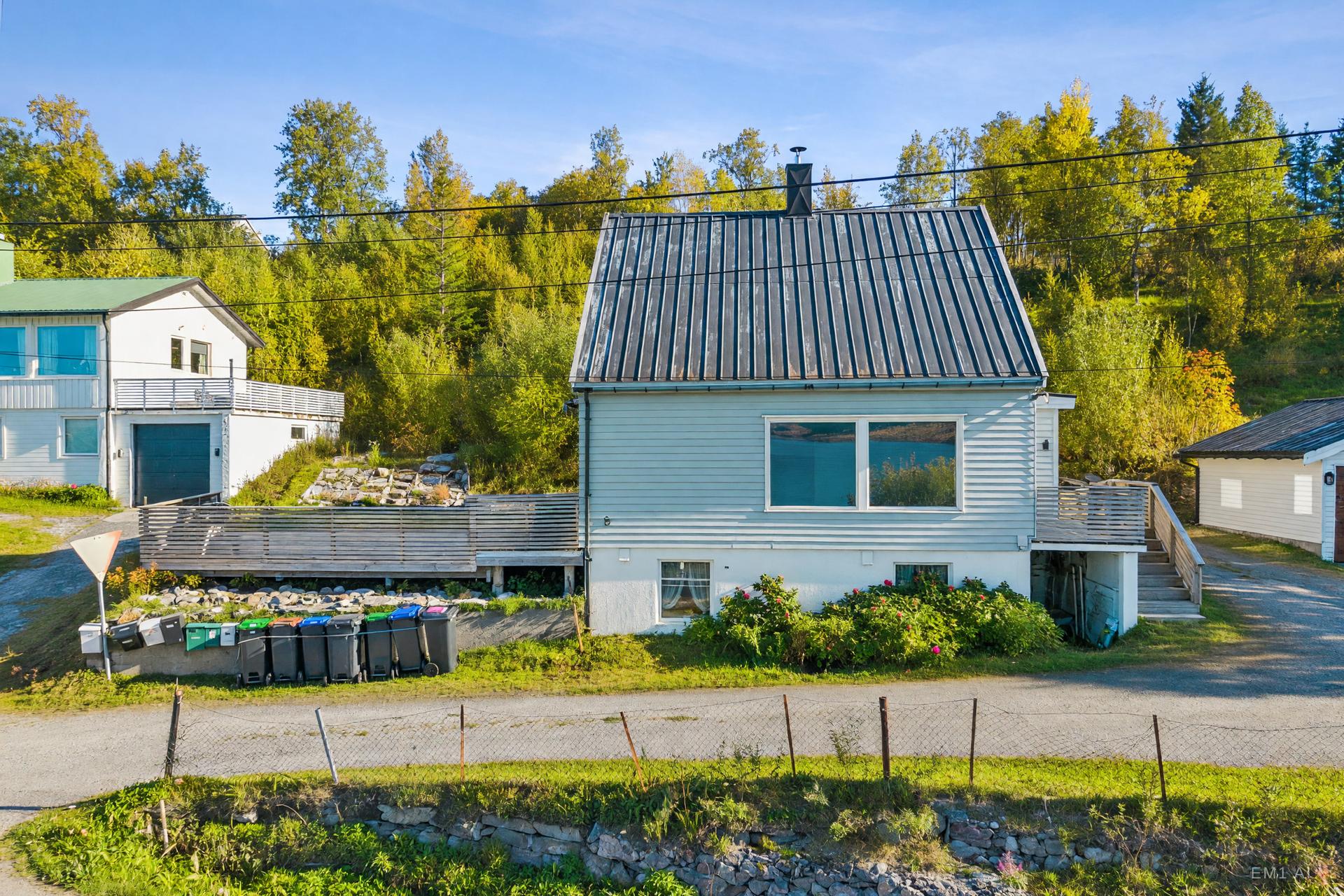 Boligen ligger fint til i hellende terreng med opparbeidet tomt og beplantning.. Bilde nummer 2 av 3