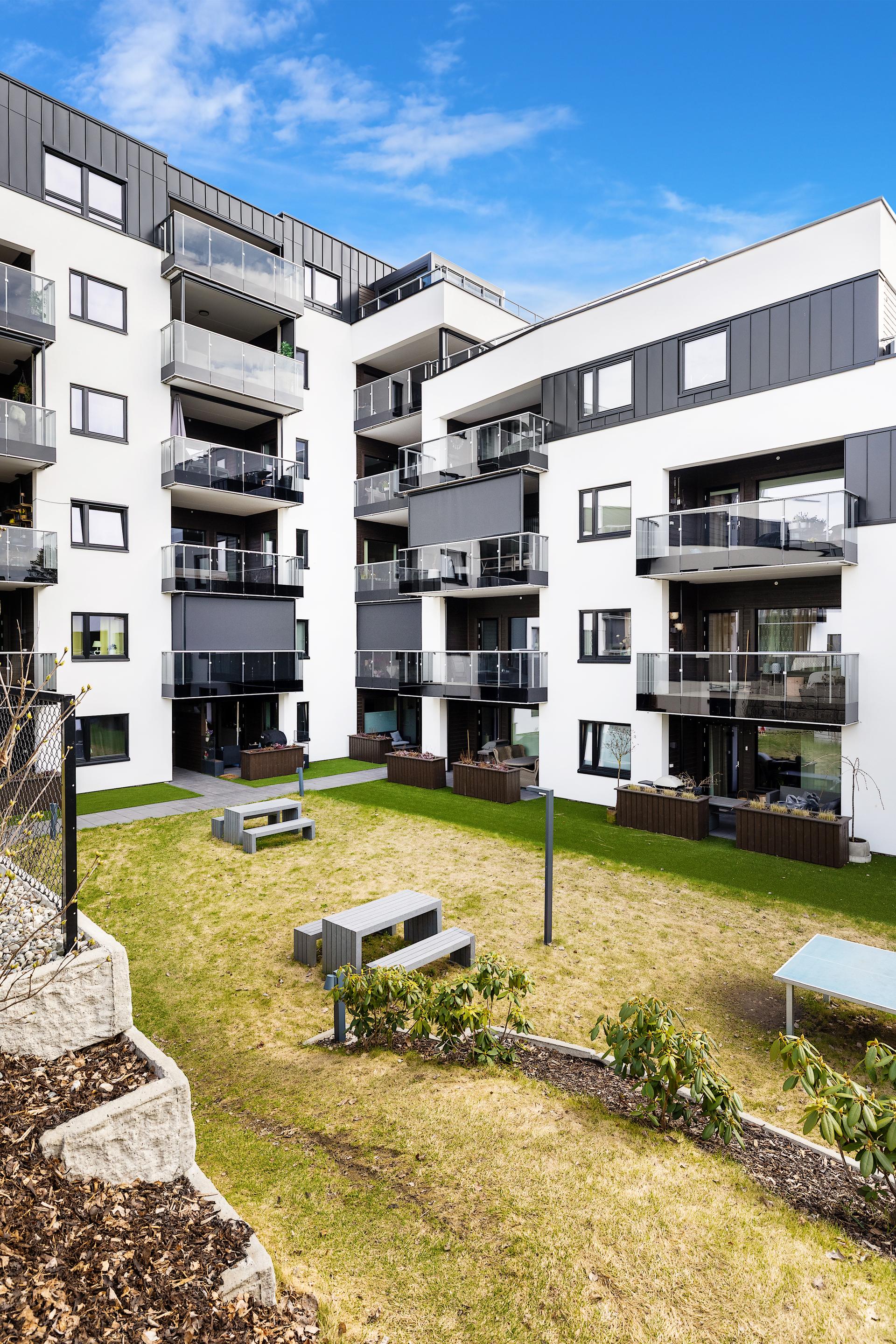 Sameiet har et pent opparbeidet atrium med plen, beplantning og sittegrupper.. Bilde nummer 2 av 3