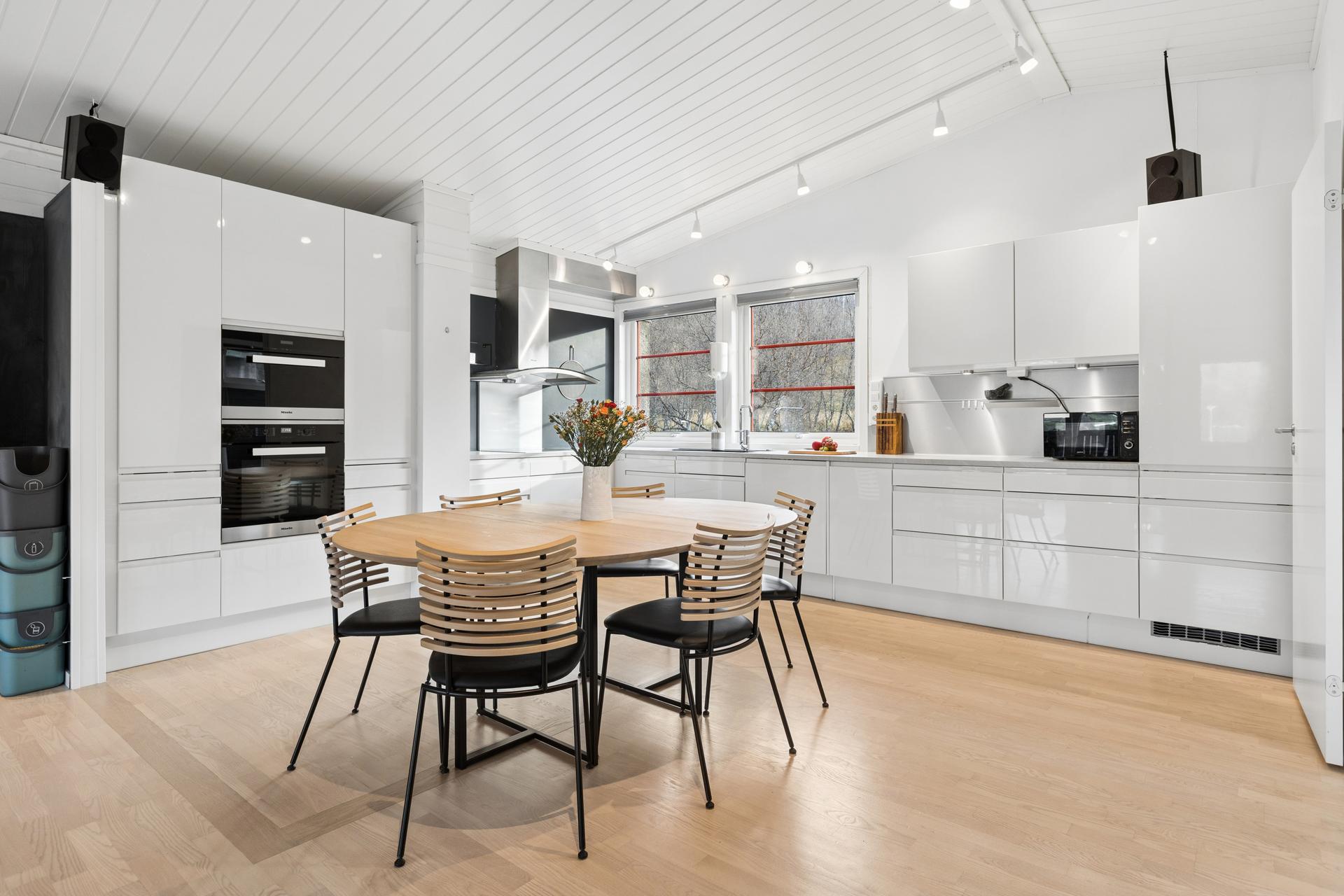 Kjøkkenet har åpen himling med downlights, integrerte Miele-stekeovner og god plass til spisebord. Bilde nummer 2 av 3