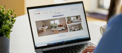 Foto av en PC som står på et bord. I forgrunnen skimter vi en person bakfra, og på skjermen er det en boligannonse.