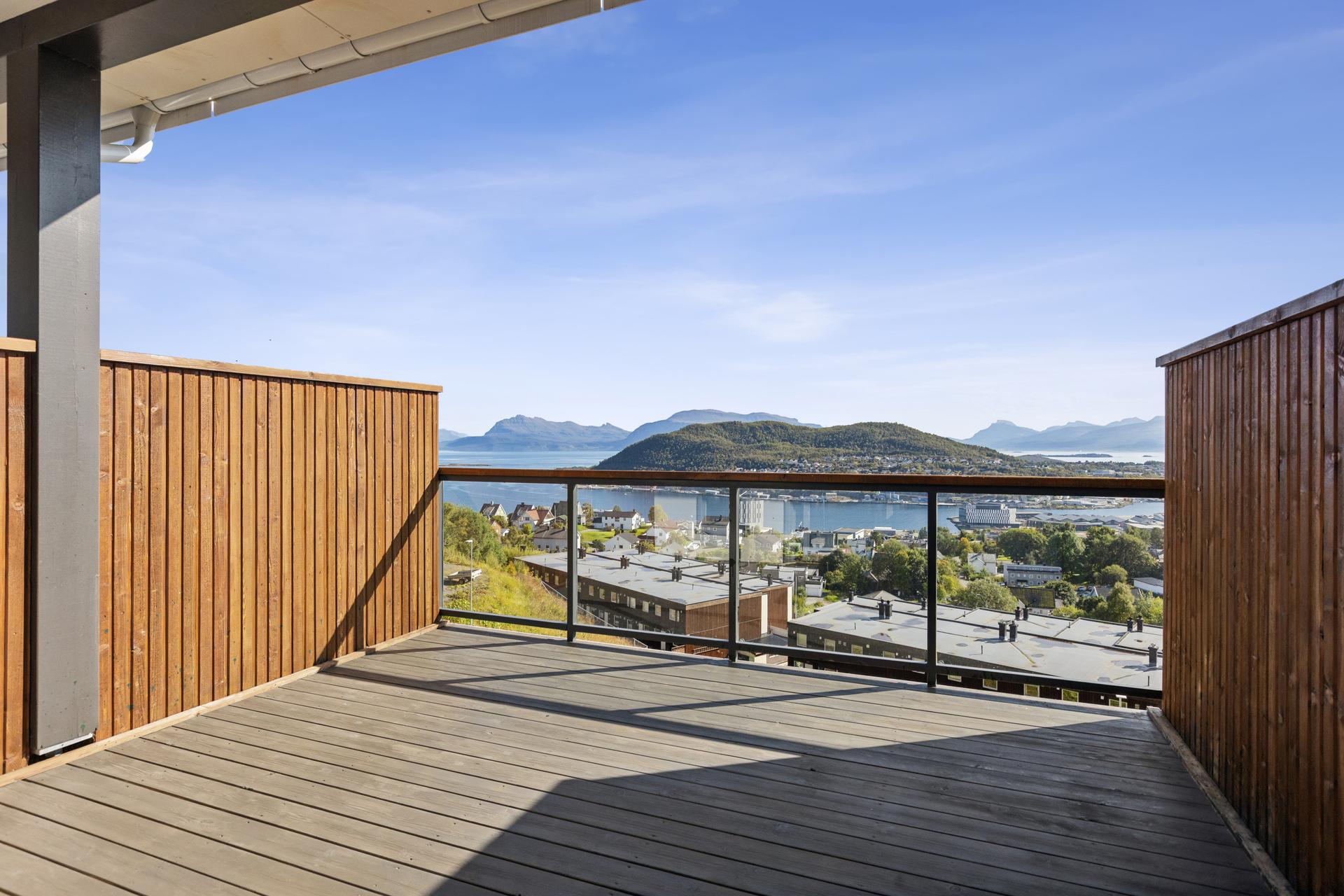 Sørøstvendt balkong med impregnert terrassedekke, glassrekkverk og utsikt mot Vågsfjorden. Bilde nummer 3 av 3