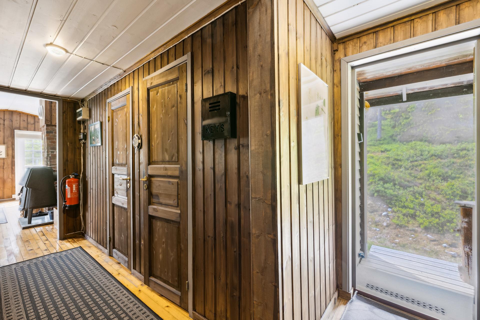 Her kommer man inn i en gang med brunmalt panel på veggene og lakkert furugulv. Gangen er romslig med god plass til å henge fra seg yttertøy og sko.. Bilde nummer 3 av 3