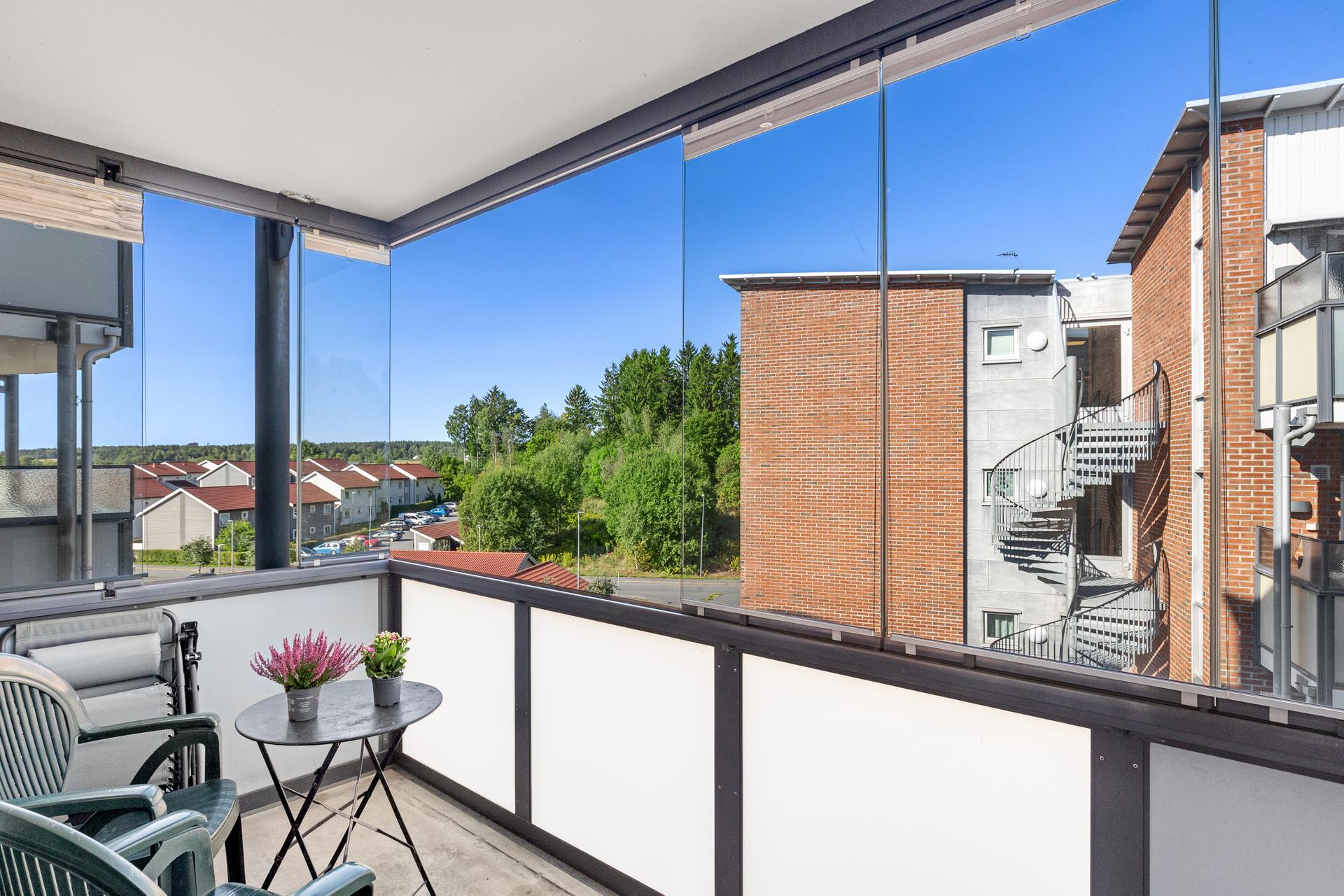 Innglasset balkong med plass til sittegruppe og fint utsyn over fellesområdene.. Bilde nummer 3 av 3