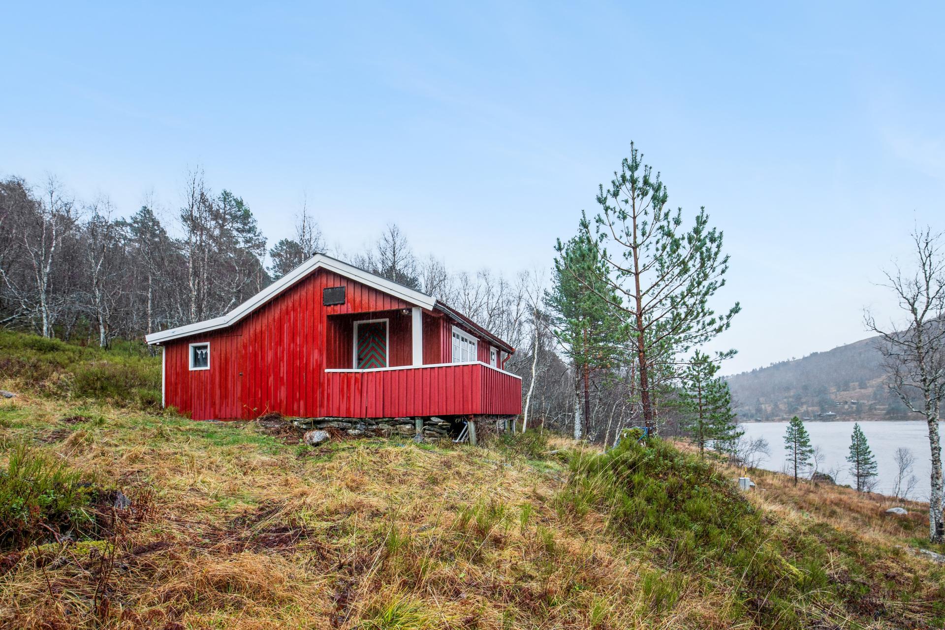 Tradisjonell fritidsbolig fra 1954, beliggende i naturskjønne omgivelser i Lunddalsvegen på Hjelset. Eiendommen ligger fritt til i skrånende terreng med vegetasjon og naturlig skjerming.. Bilde nummer 3 av 3
