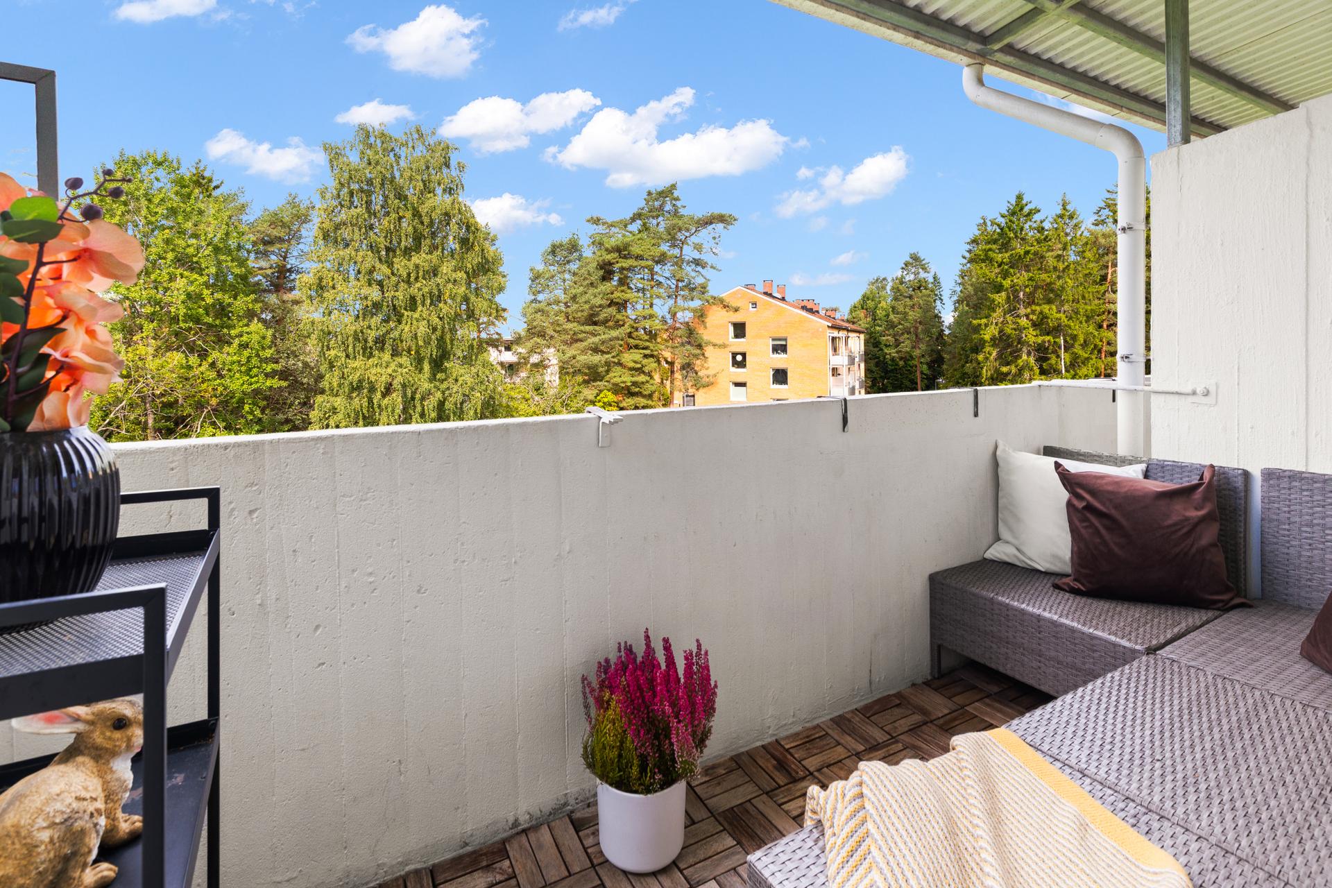 Velkommen til Mellombølgen 28. Foto: John Løvås. Koselig, nordvestvendt overbygget balkong med treheller på dekket og skjermende glassfelt mot siden.. Bilde nummer 1 av 3