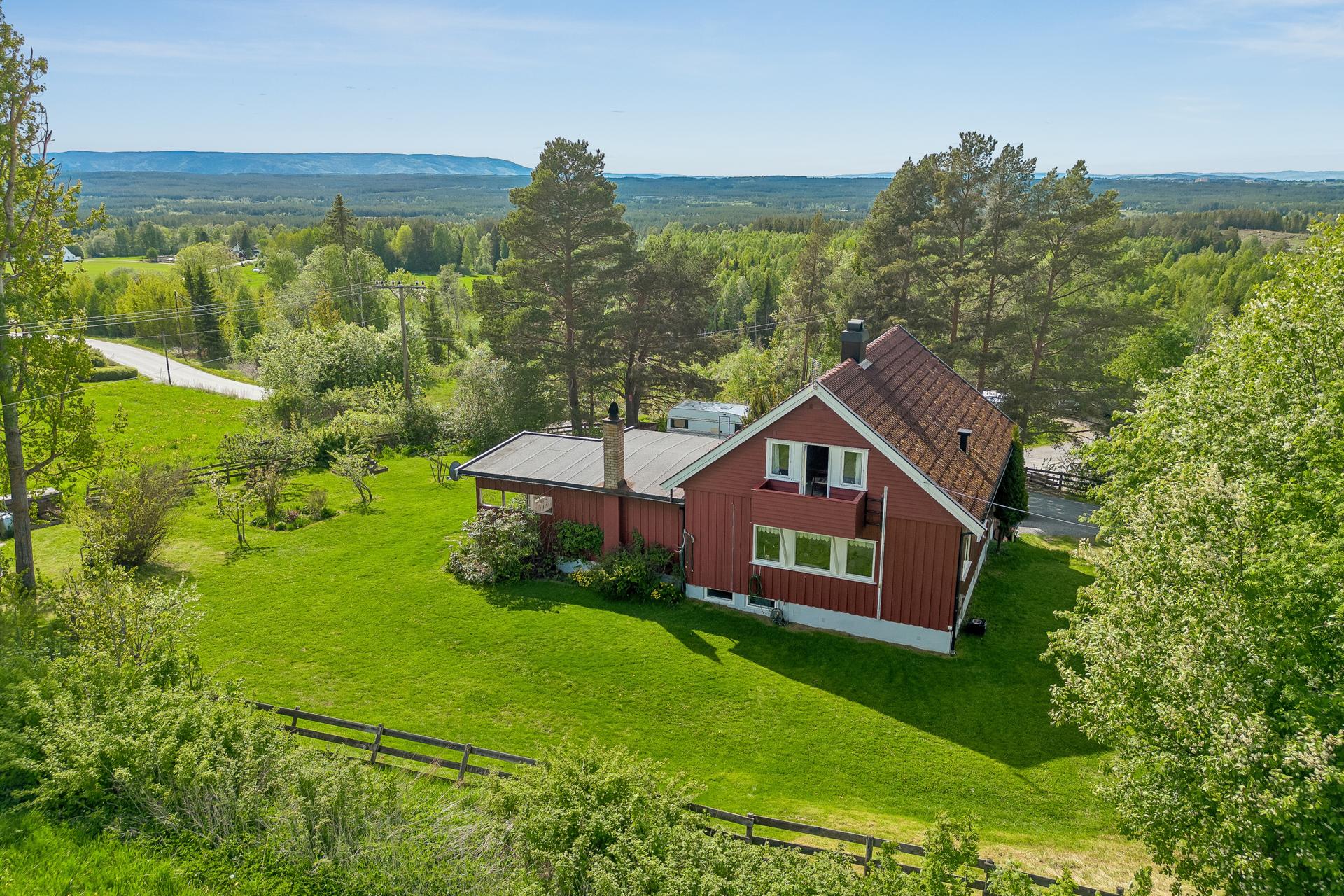 Eiendommen ligger på en romslig, skrånende tomt med hageanlegg, plen og variert beplantning.. Bilde nummer 1 av 3