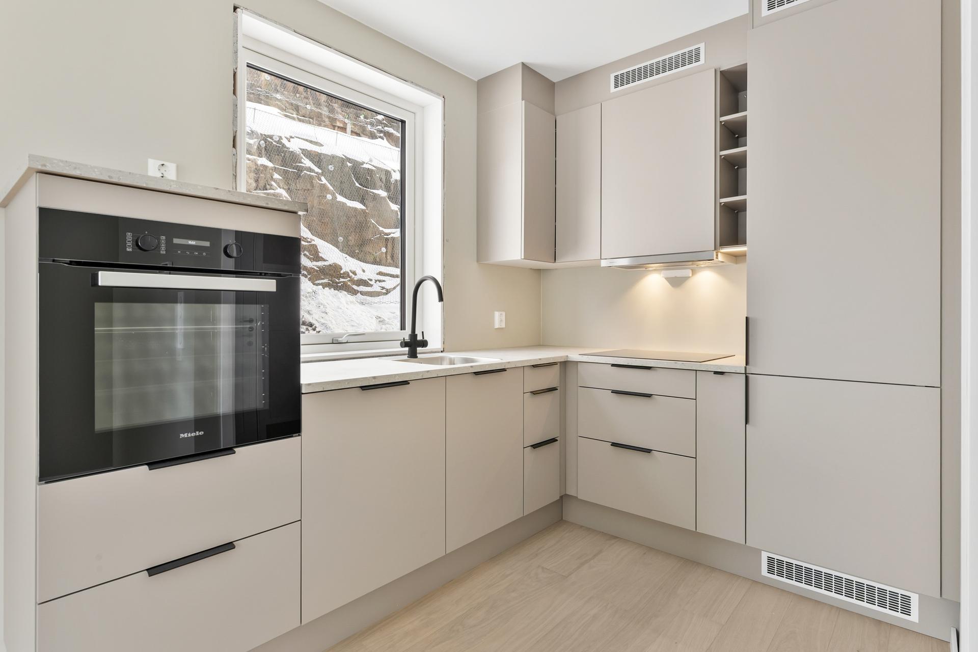 Moderne kjøkken med integrerte hvitevarer som stekeovn, platetopp, oppvaskmaskin og kombiskap fra Miele. . Bilde nummer 2 av 3
