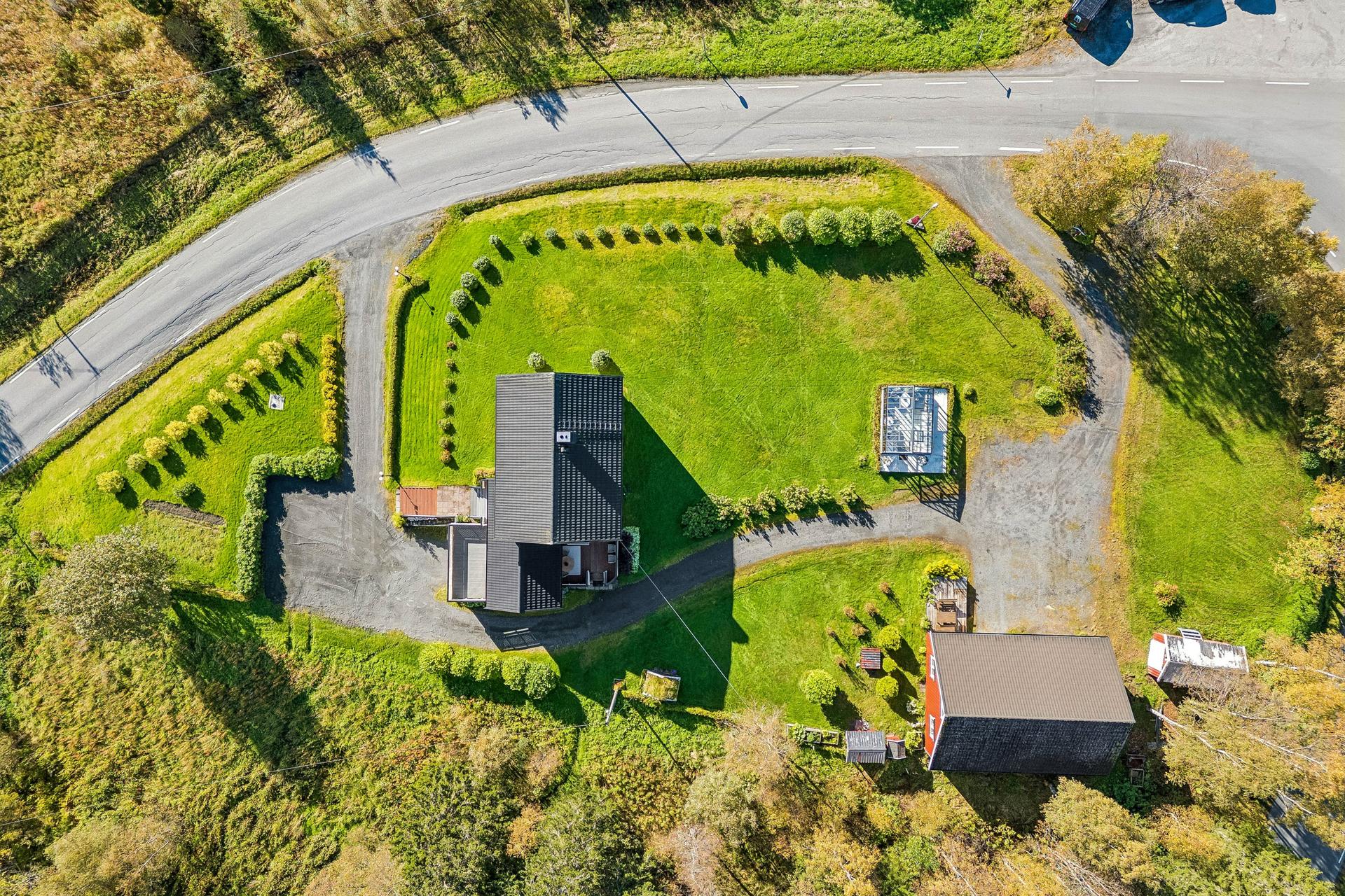 Tomten er flat og pent opparbeidet med plenarealer, trær og beplantning.. Bilde nummer 2 av 3