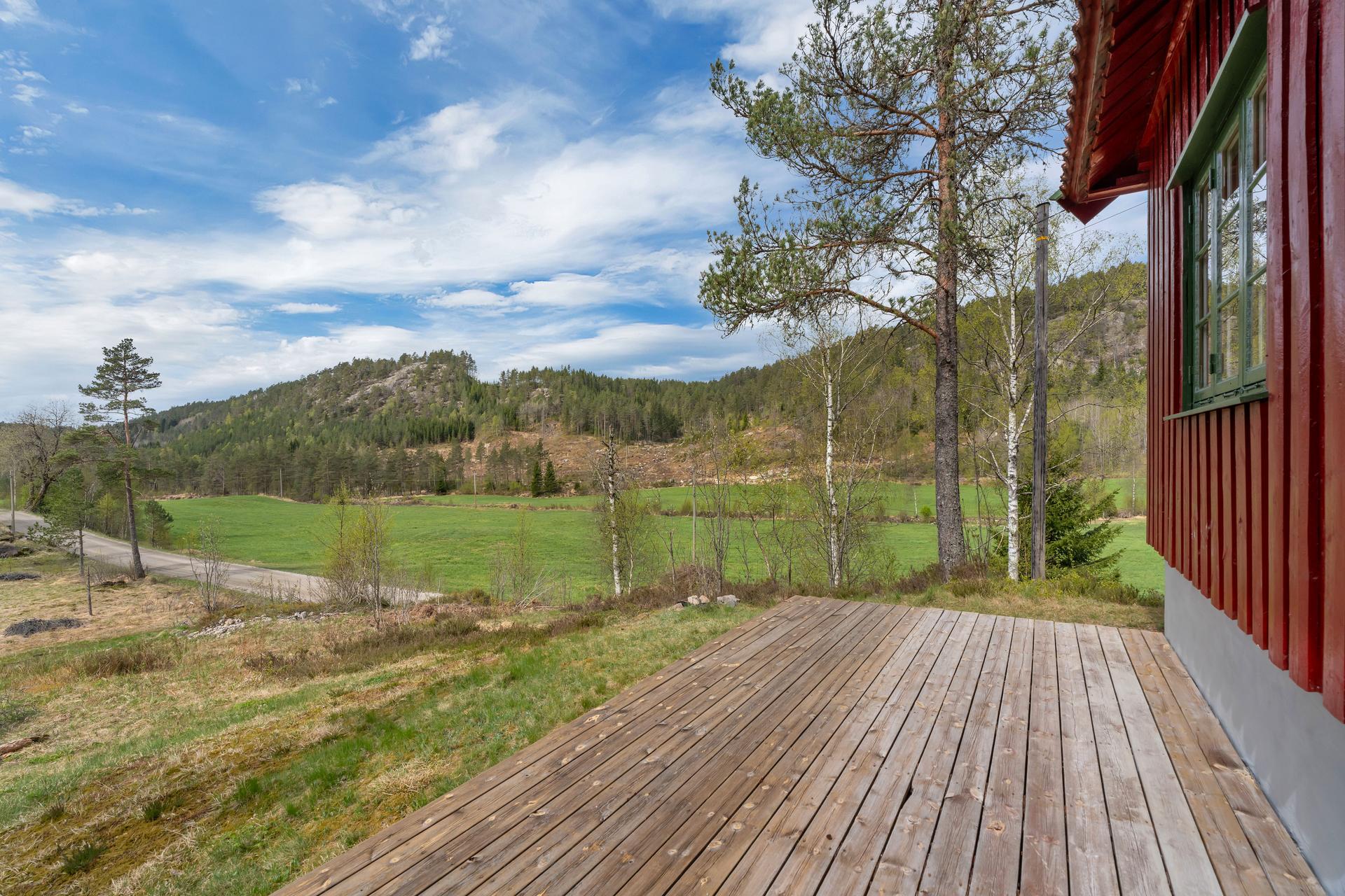 Eiendommen ligger idyllisk til i rolige og naturskjønne omgivelser, med en treplatting som vender ut mot landskapet.. Bilde nummer 2 av 3