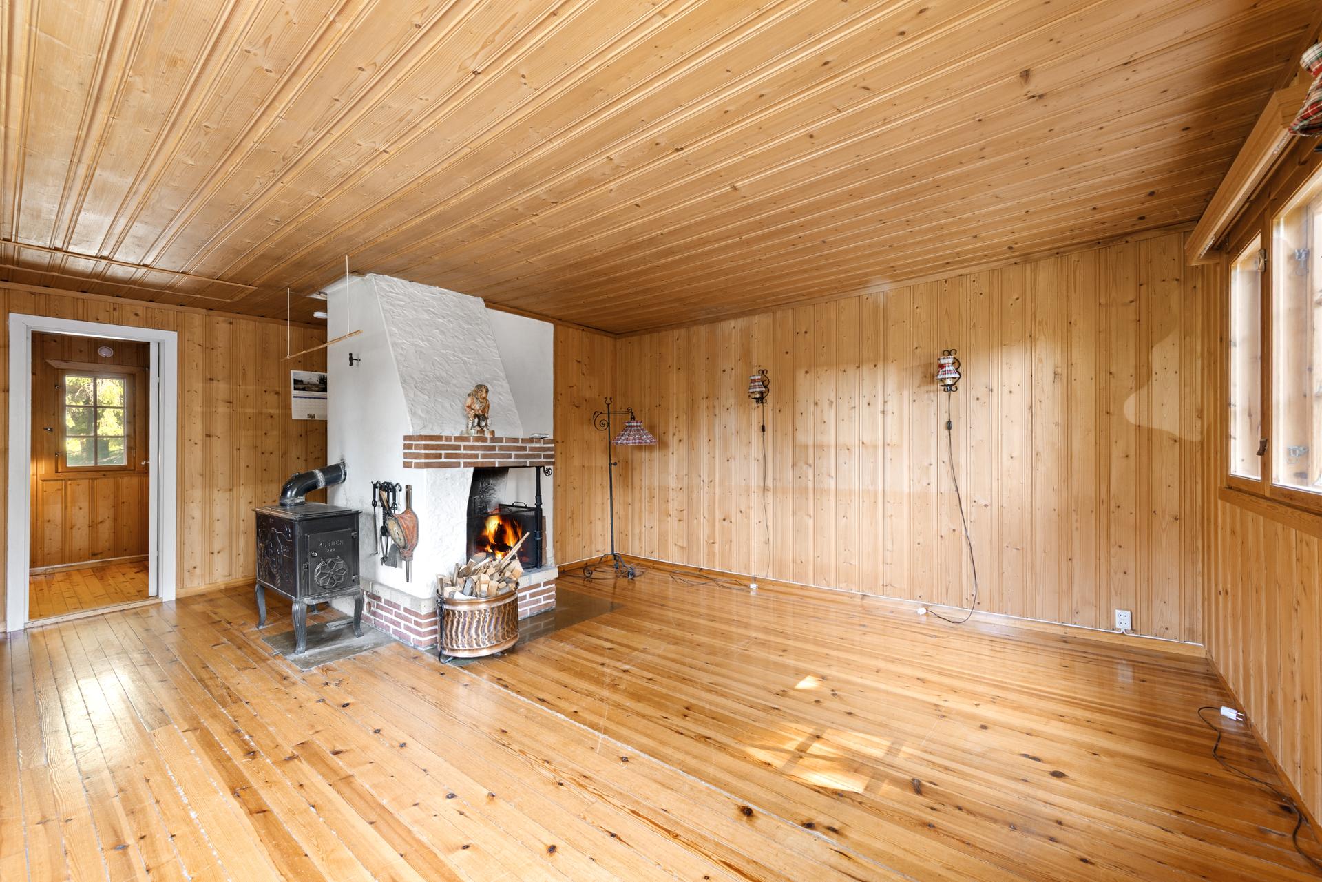 Hyttas samlingspunkt med både åpen peis og vedovn for varme og hygge.. Bilde nummer 2 av 3
