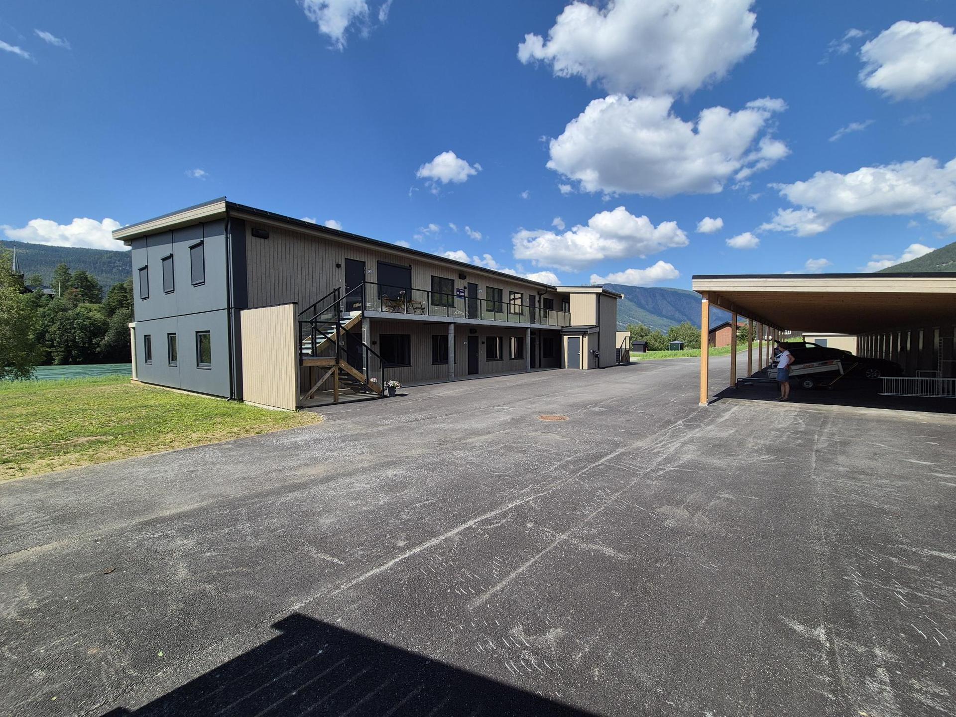 Bygget sett fra nede ved brukaret. Carport-anlegg med bod i bakkant til høyre i bildet. Bilde nummer 3 av 3