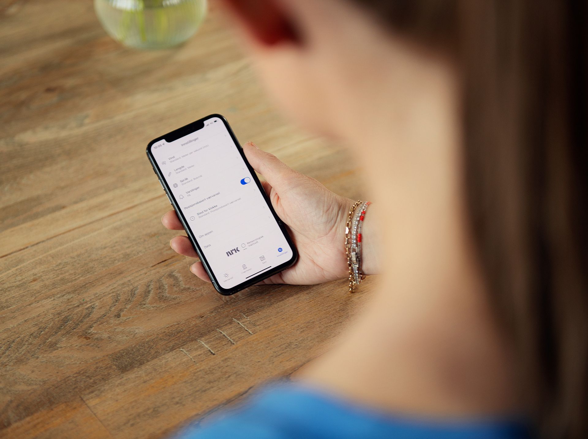 Hånd som holder i en mobil med skjermen mot kamera. Foto.
