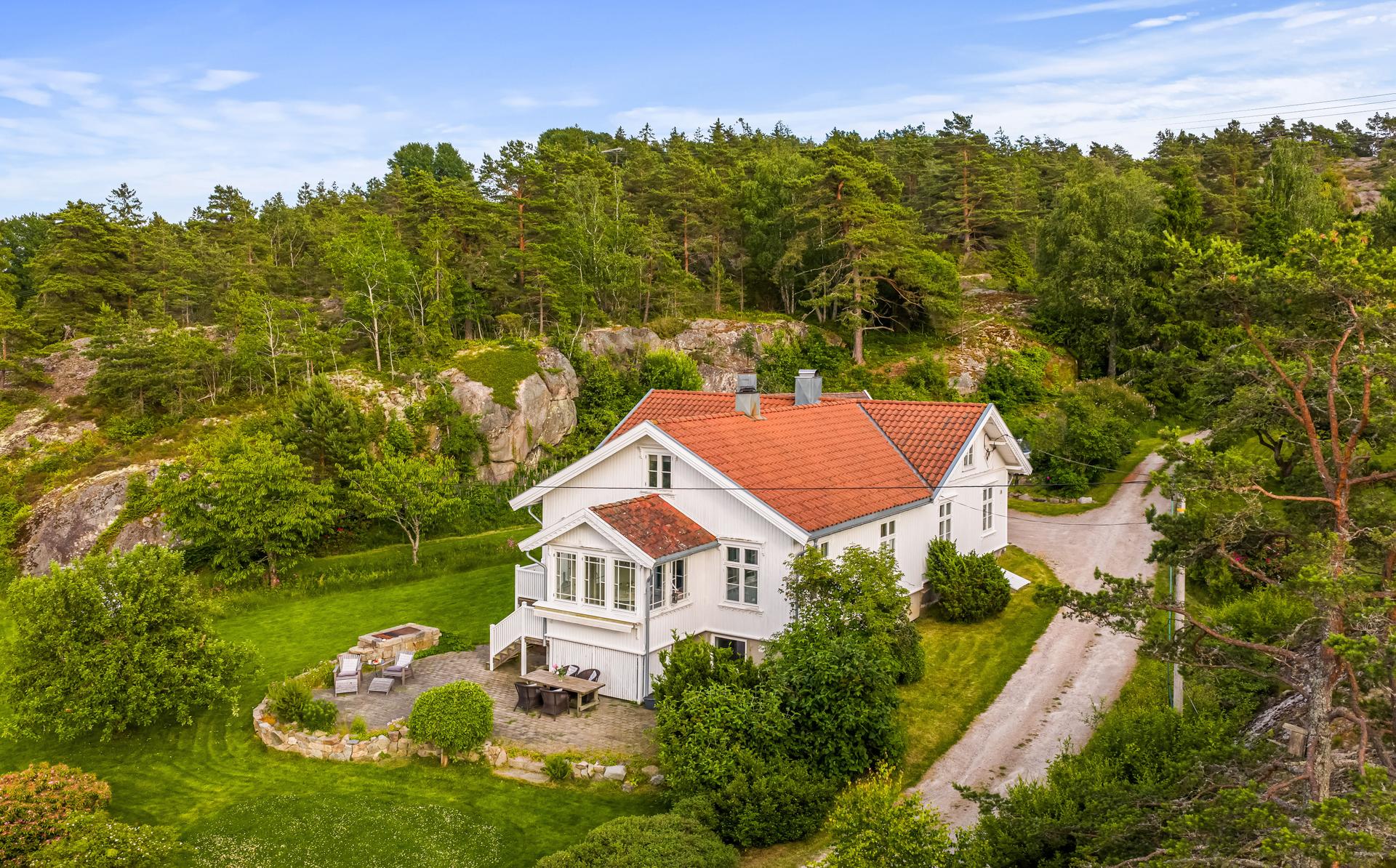 Eiendommen ligger skjermet til, omgitt av skog og svaberg i et klassisk kystlandskap.. Bilde nummer 2 av 3