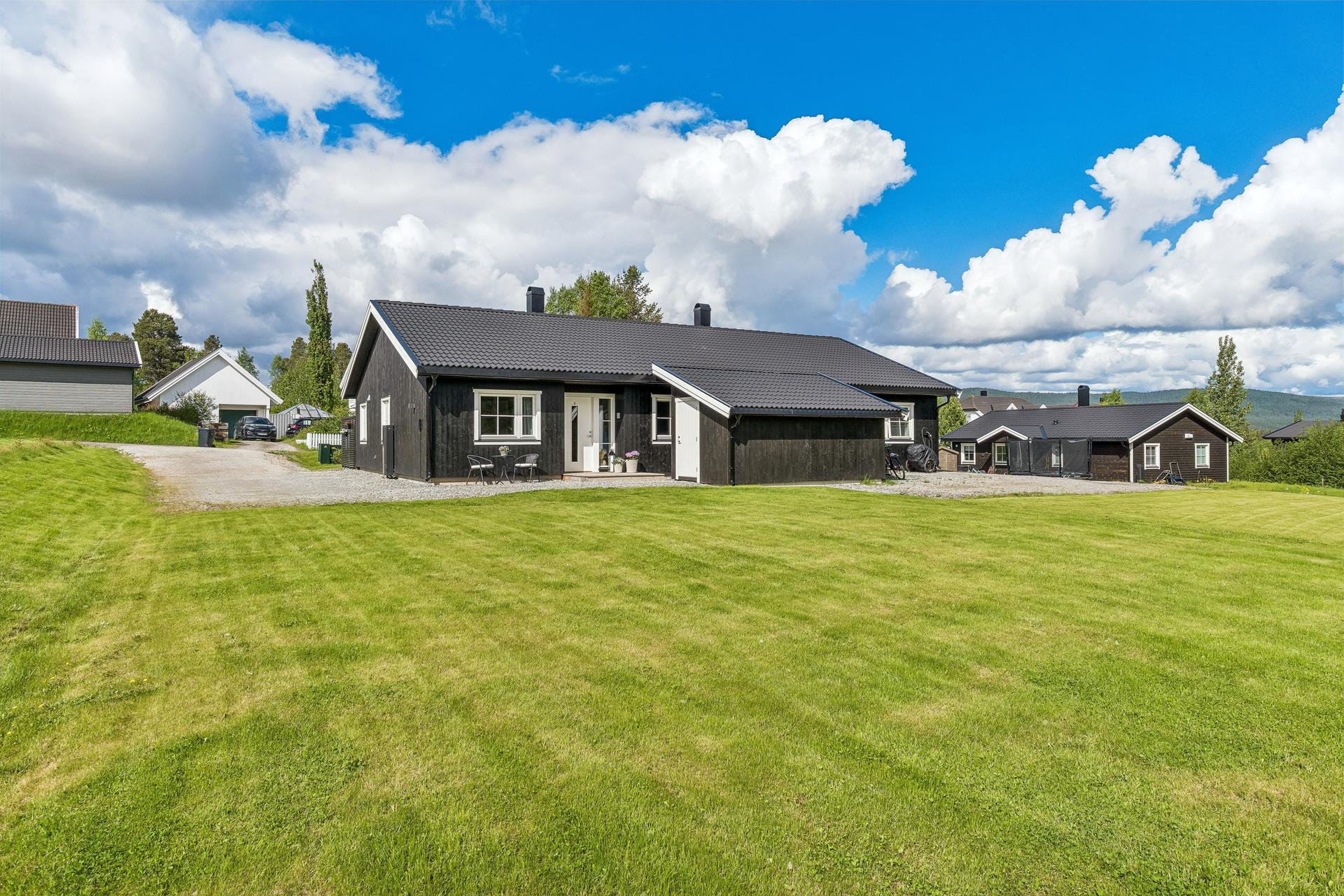 Boligen er omgitt av åpne grøntarealer. Parkeringplass inntil husveggen.  . Bilde nummer 2 av 3