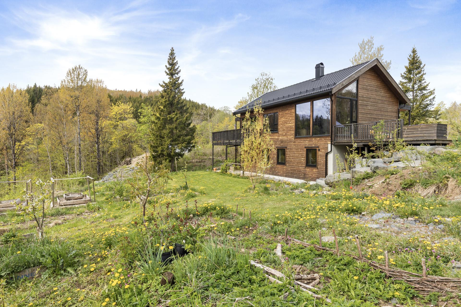 Eiendommen har en 997 m² stor eiet tomt. Tomten er en kupert og skrånende naturtomt med gressplen og beplantning, samt fjellknauser. På eiendommen er det opparbeidet flere flotte uteplasser.. Bilde nummer 2 av 3