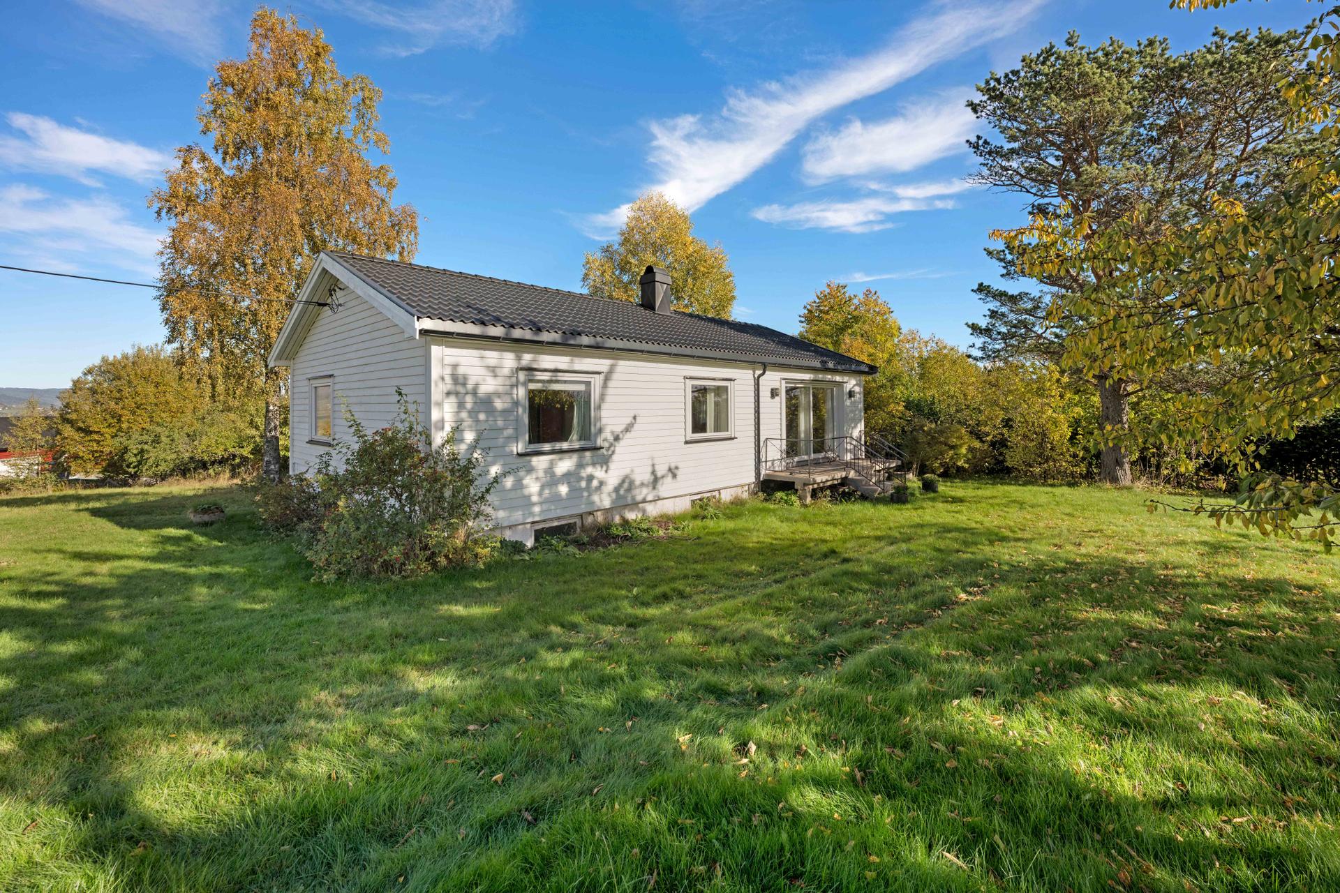 Eneboligen ligger fritt plassert på tomten med åpen hage rundt huset.. Bilde nummer 2 av 3