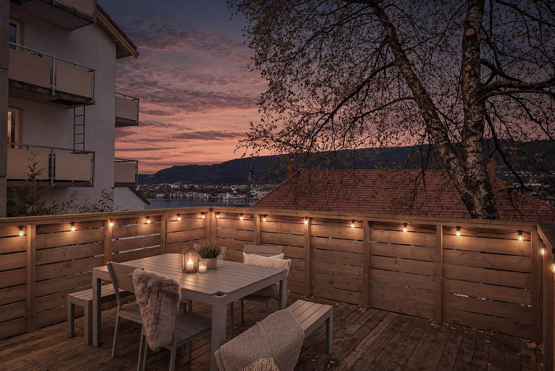 Felles terrasse med sittegruppe og utsyn mot fjorden. Her ser vi over mot Nordnes og Verftet.  Megakoselig om kvelden!. Bilde nummer 3 av 3