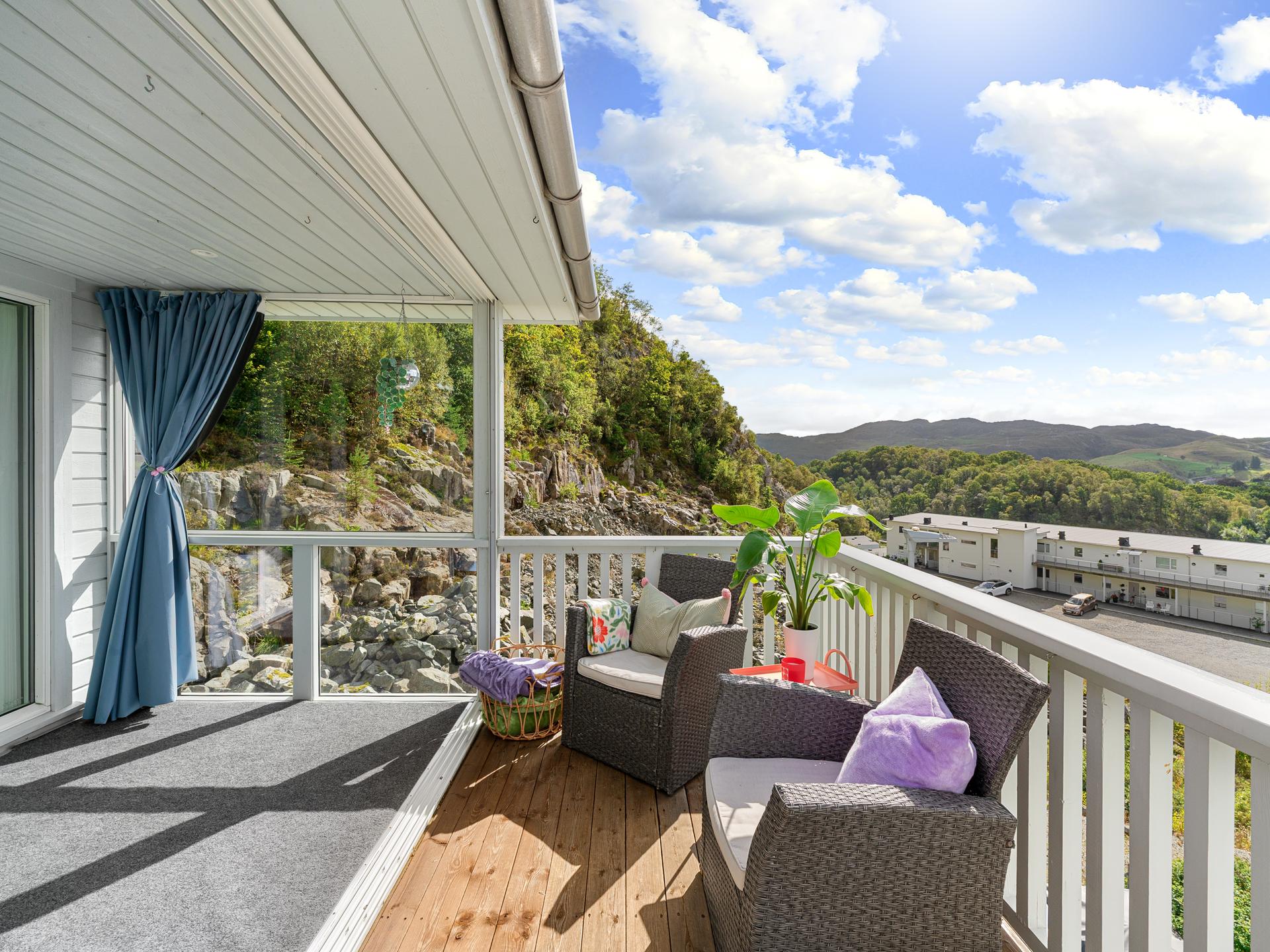 Uteplassen har terrassebord i tre og rekkverk med flott utsikt mot sentrum og Edlandsfjellet . Bilde nummer 3 av 3