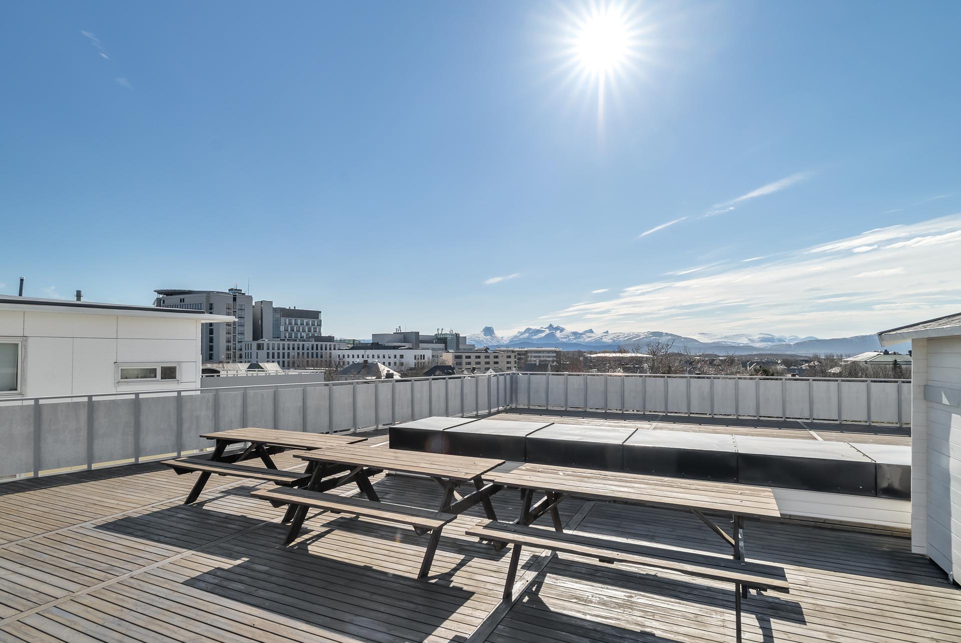 Felles takterrasse med sittegrupper og vidstrakt utsikt mot fjellene rundt Bodø. Bilde nummer 3 av 3