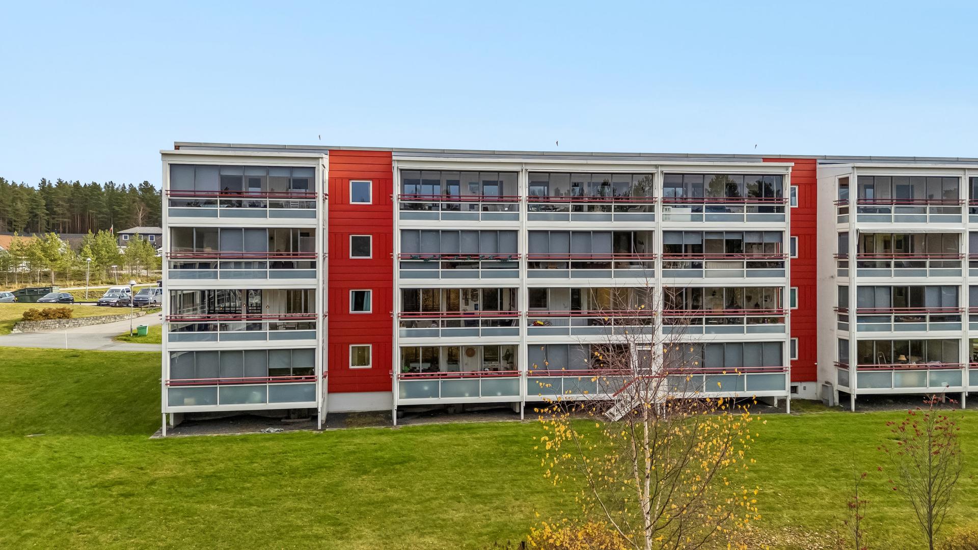 Fasaden mot vest med de innglassede balkongene vendt ut mot grønne fellesområder.. Bilde nummer 2 av 3