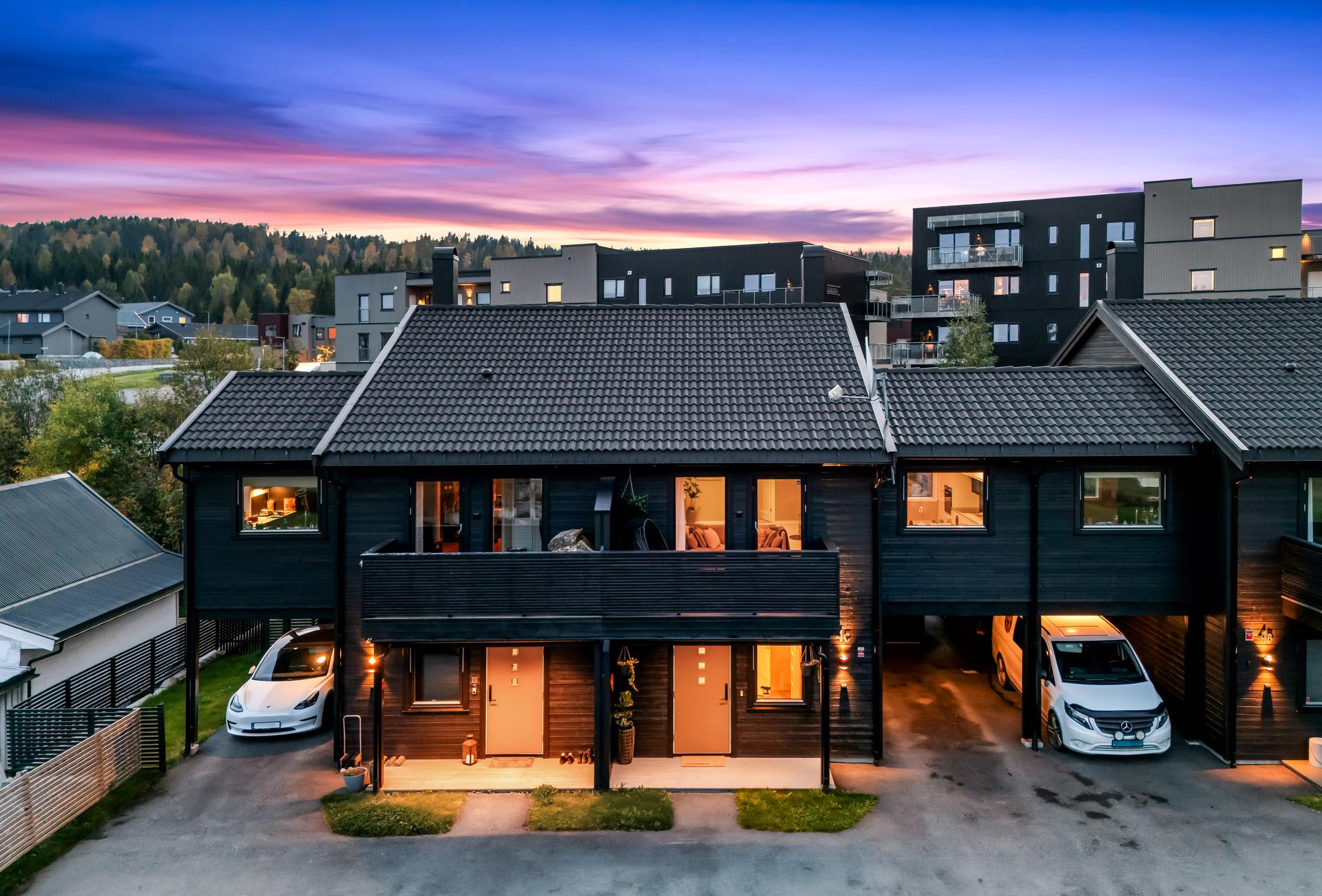 Stemningsfull kveldsbelysning langs inngangspartiene og carportene.. Bilde nummer 2 av 3