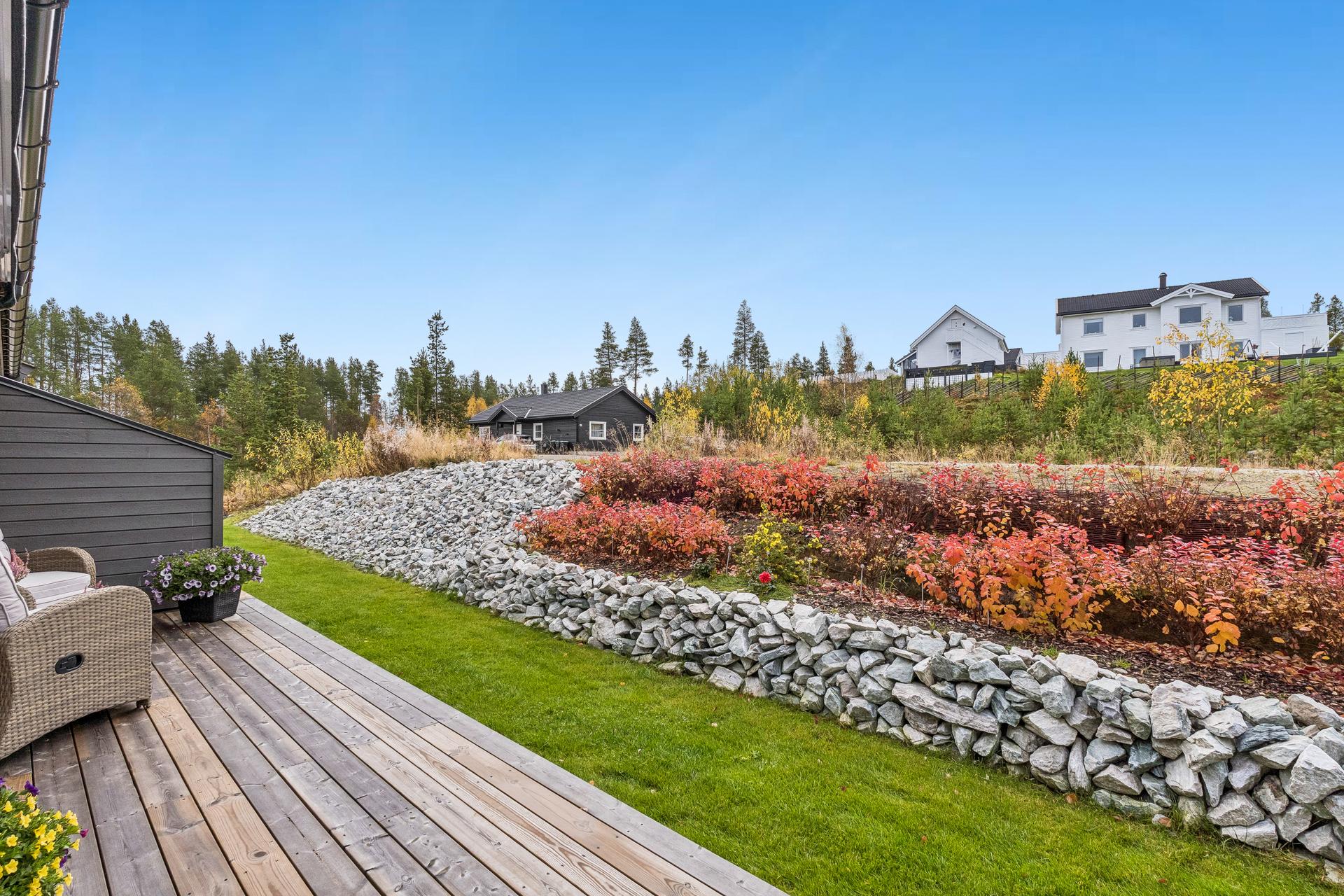 Pent opparbeidet hageområde med steinmur, beplantning og plen.. Bilde nummer 3 av 3
