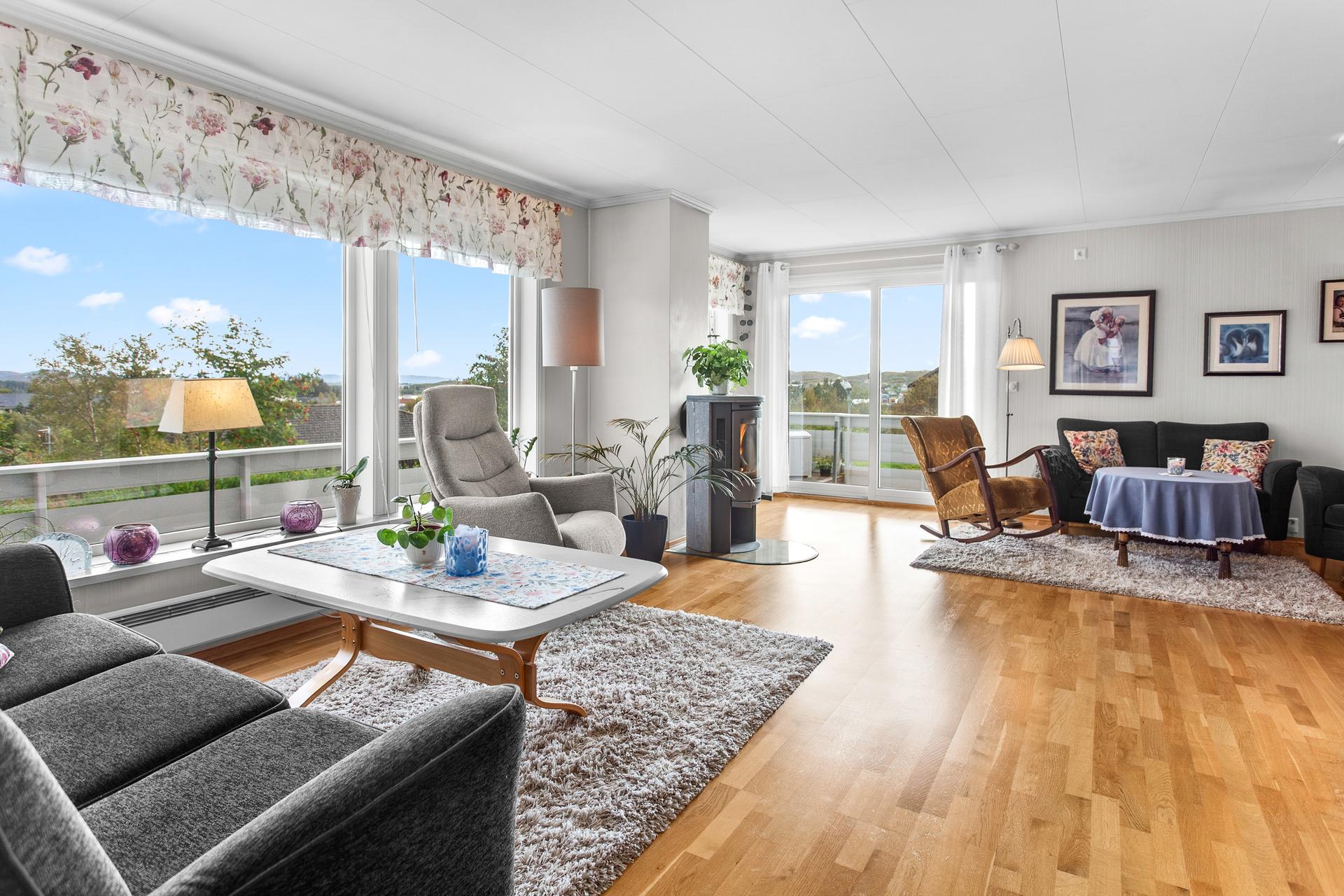Lys stue med store vindusflater, vedovn og direkte utgang til uteplassen.. Bilde nummer 3 av 3