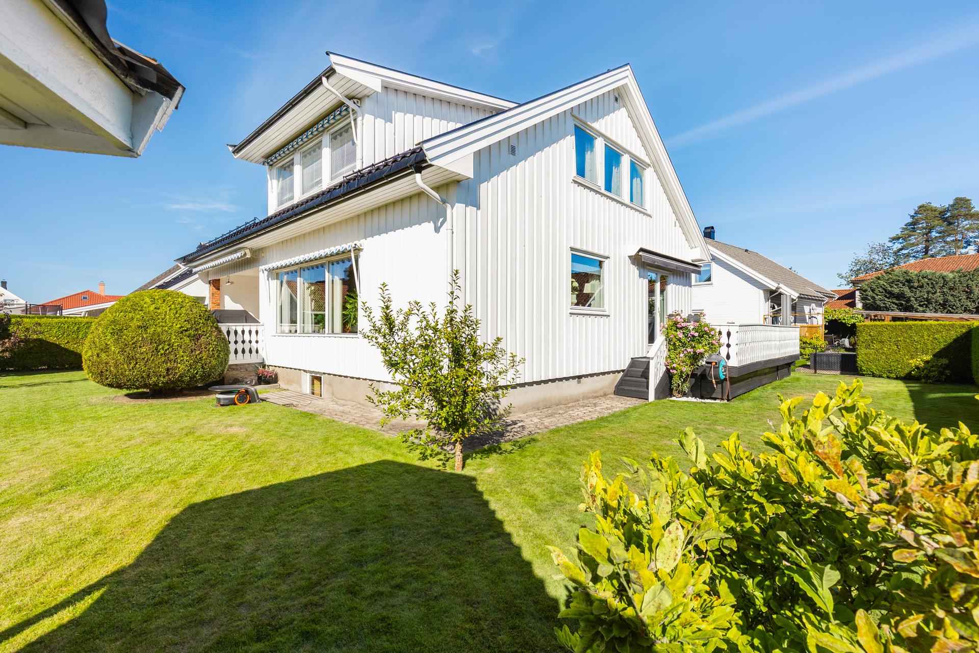 Eiendommen har en flat, usjenert hage omkranset av hekk og flere opparbeidede uteplasser.. Bilde nummer 3 av 3