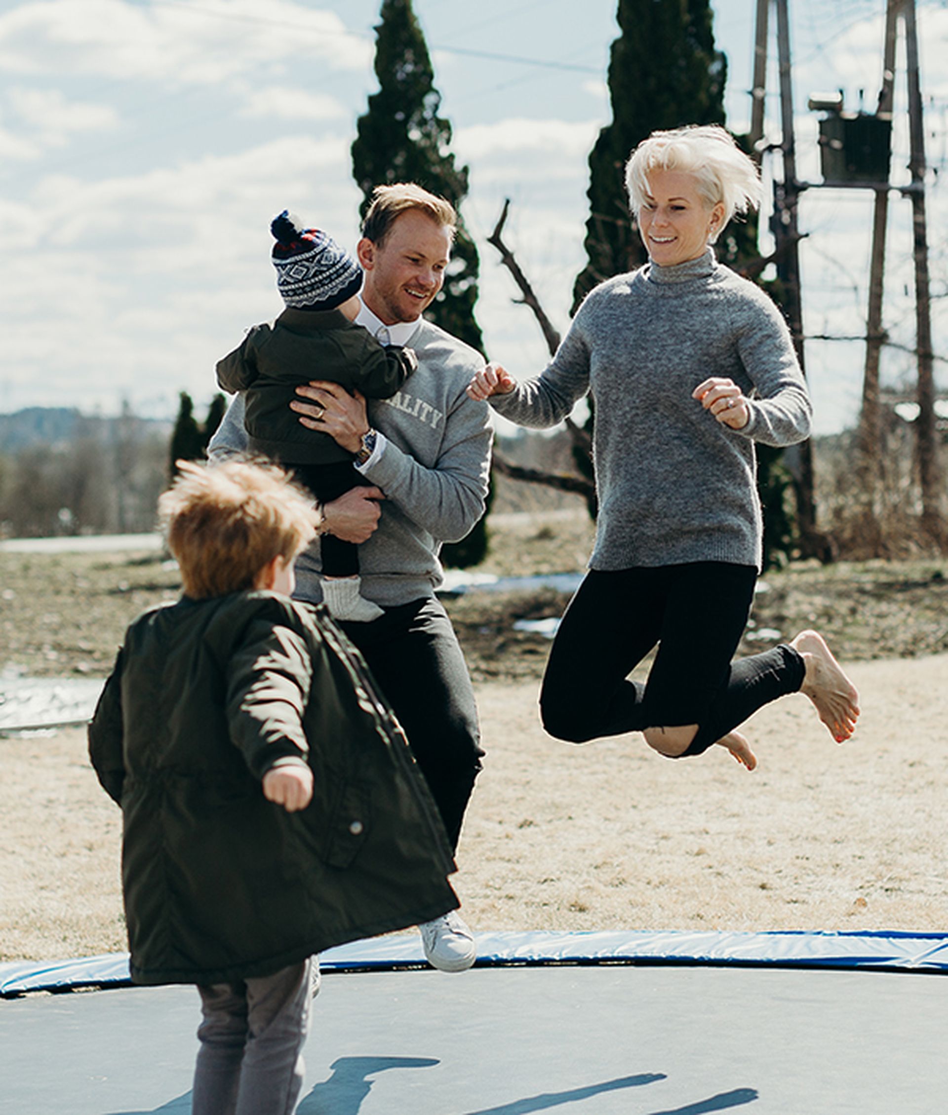 Foreldre og to barn hopper på trampoline. Bilde.