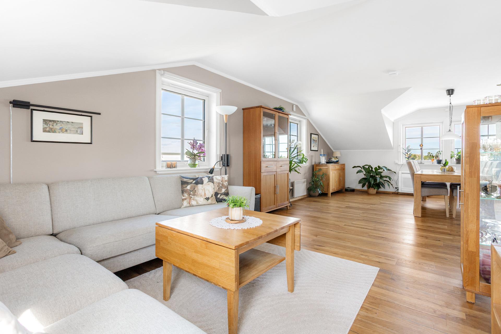 Romslig stue med plass til flere sittegrupper og stort spisebord. Bilde nummer 2 av 3