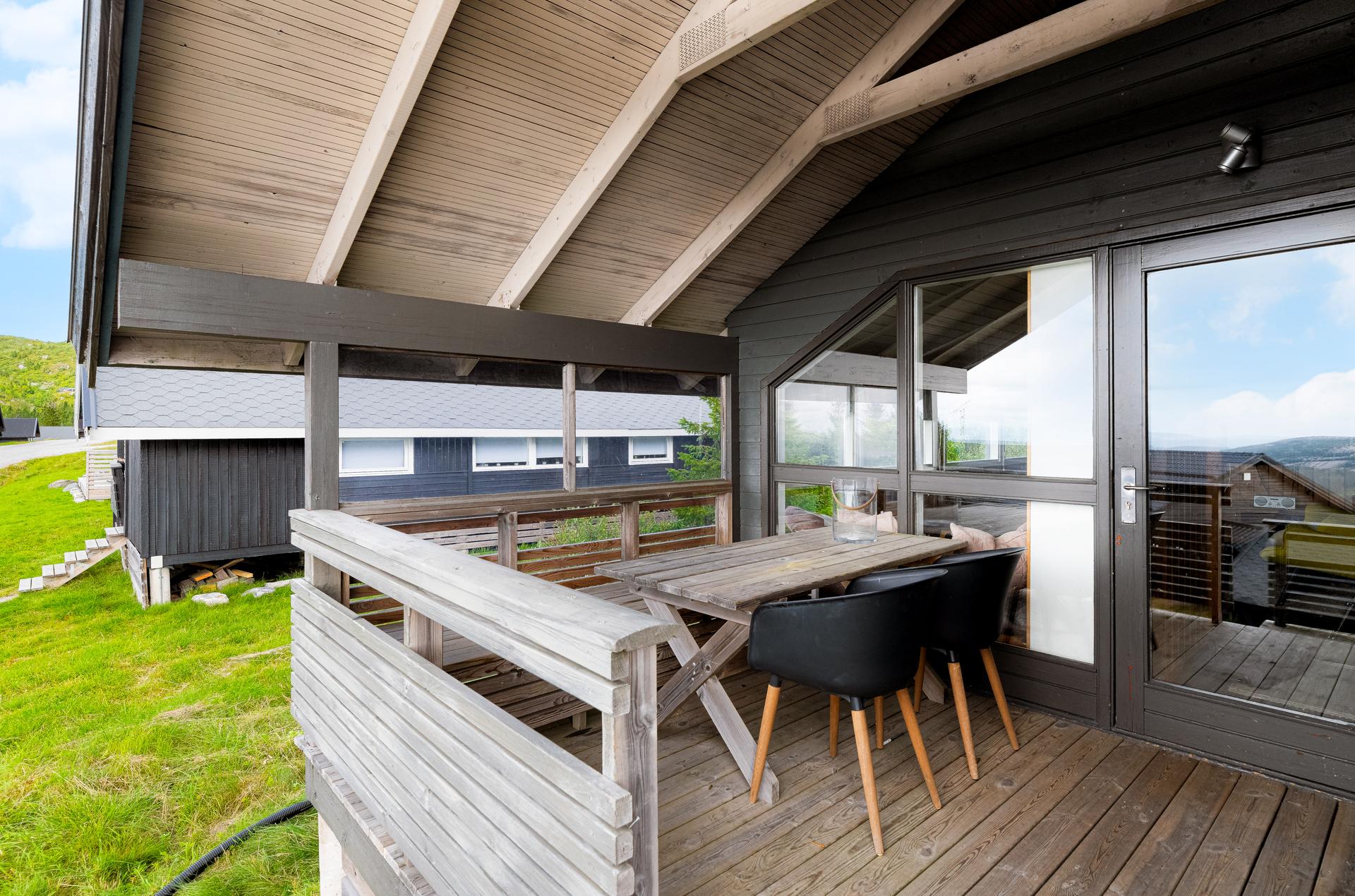Vestvendt overbygd terrasse ved inngangspartiet med en lun sitteplass hvor det er ettermiddagssol og nydelig utsikt.. Bilde nummer 3 av 3