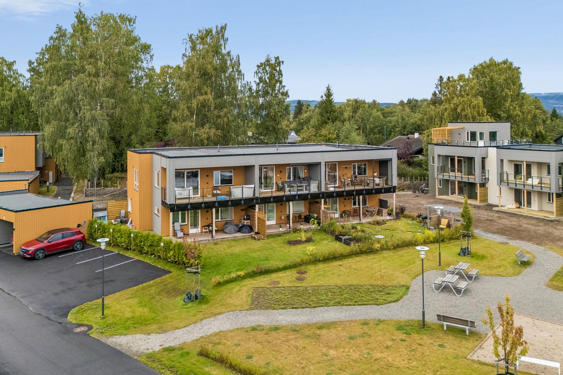 Rekkehus fra 2024 over to plan med overbygde uteplasser og hage i et etablert bomiljø.. Bilde nummer 3 av 3