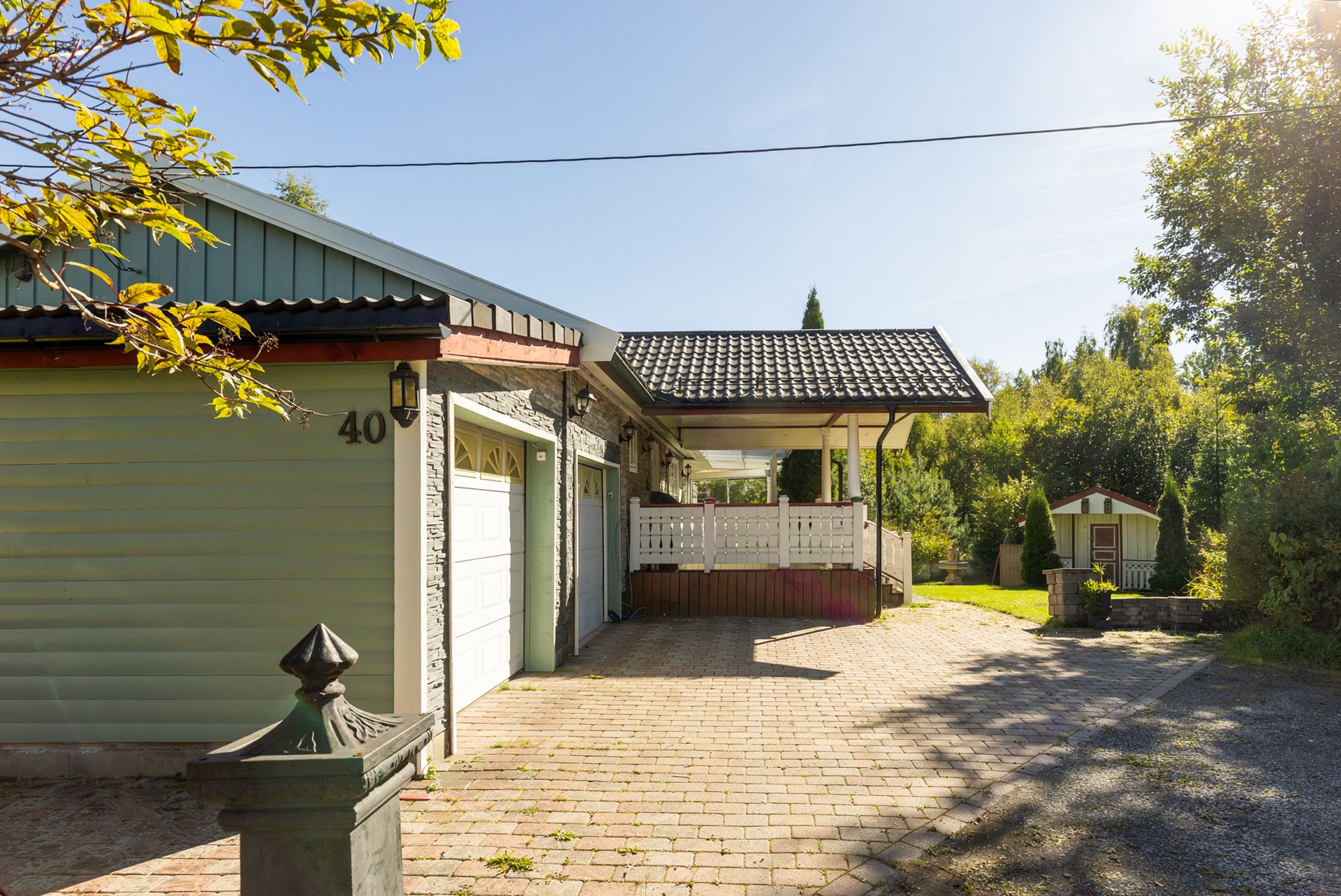 Romslig steinlagt gårdsplass foran garasjene.. Bilde nummer 2 av 3