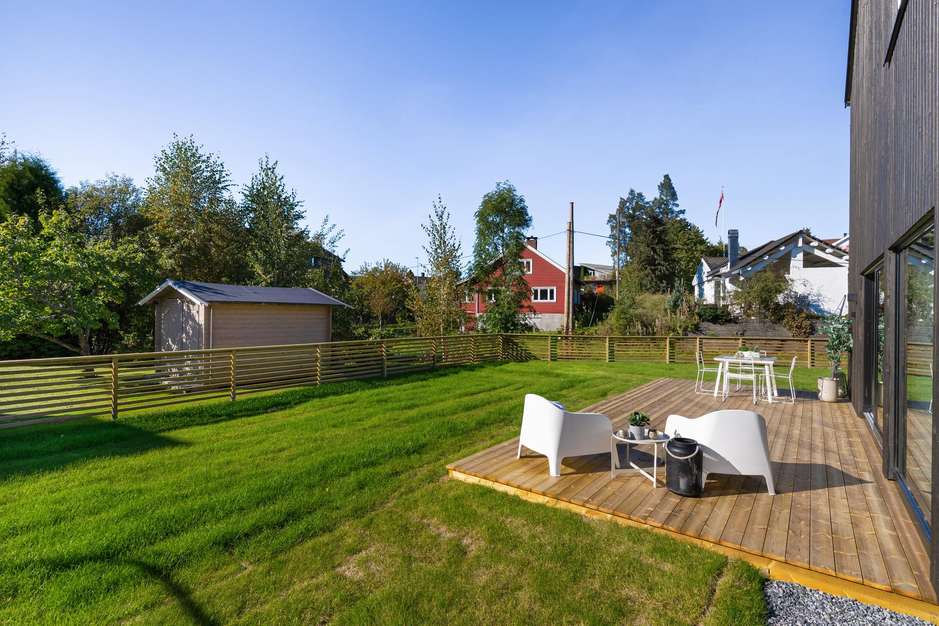 Boligen er også ferdig opparbeidet utendørs, her med markterrasse utenfor stuedelen, og med ferdig gressplen og inngjerding i front og på siden av boligen. . Bilde nummer 2 av 3