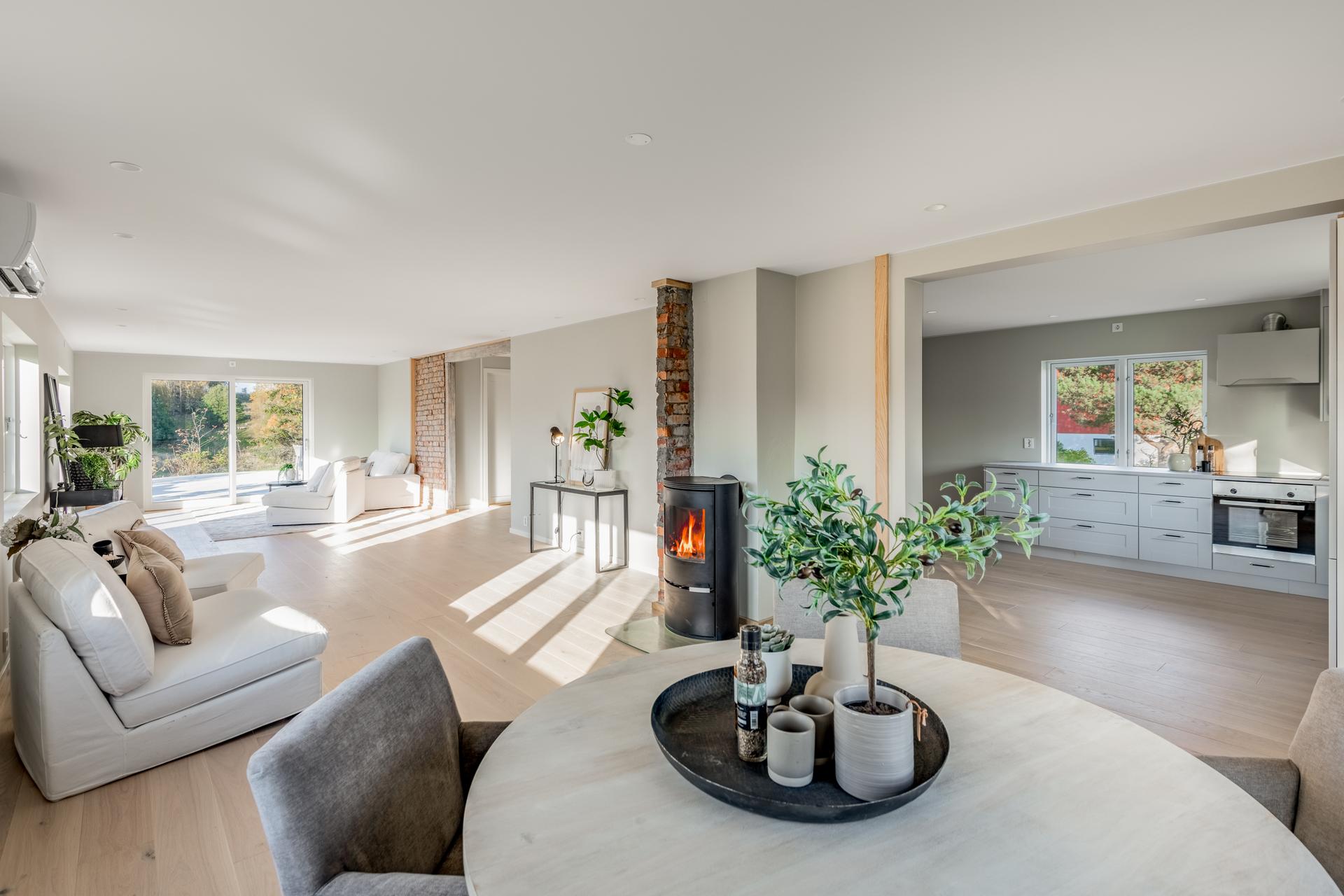 Første etasje har en åpen planløsning med gjennomgående parkett, downlights i tak, vedovn tilknyttet teglsteinspipe og utgang til støpt uteplass.. Bilde nummer 3 av 3